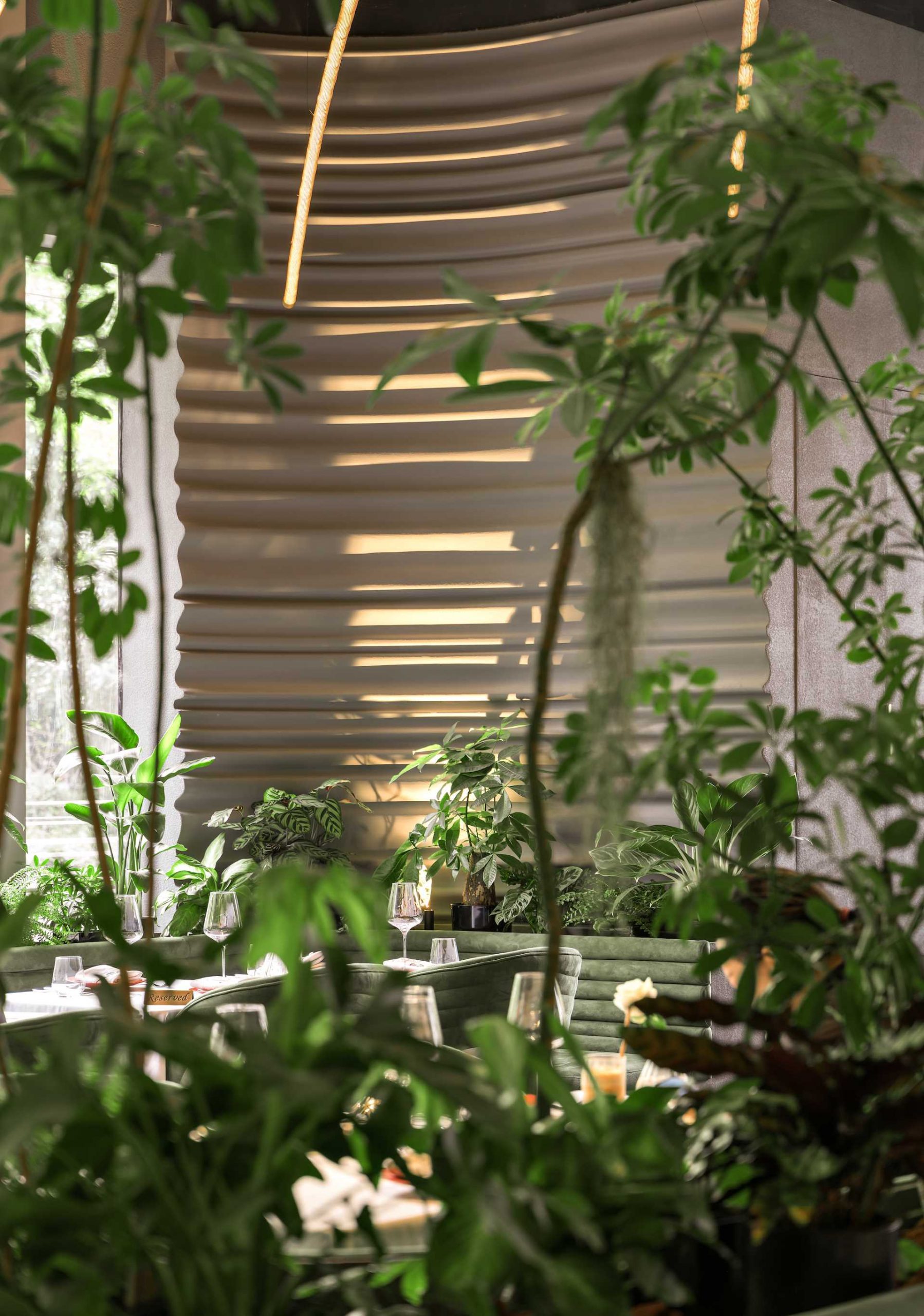 A modern restaurant filled with plants and sculptural walls.