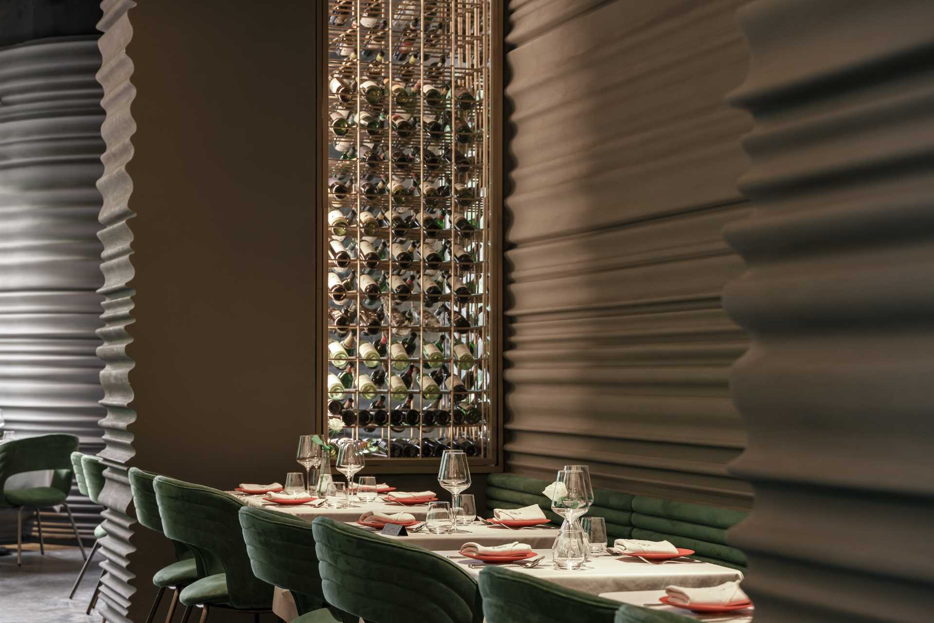 A modern restaurant with sculptural walls and built-in wine racks.