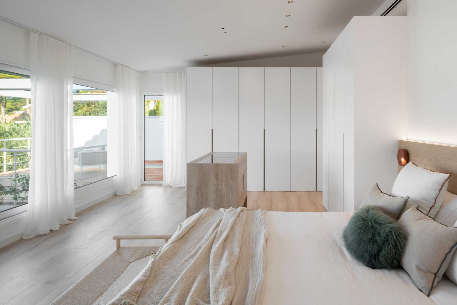 A modern white bedroom with oak floors and white closets.