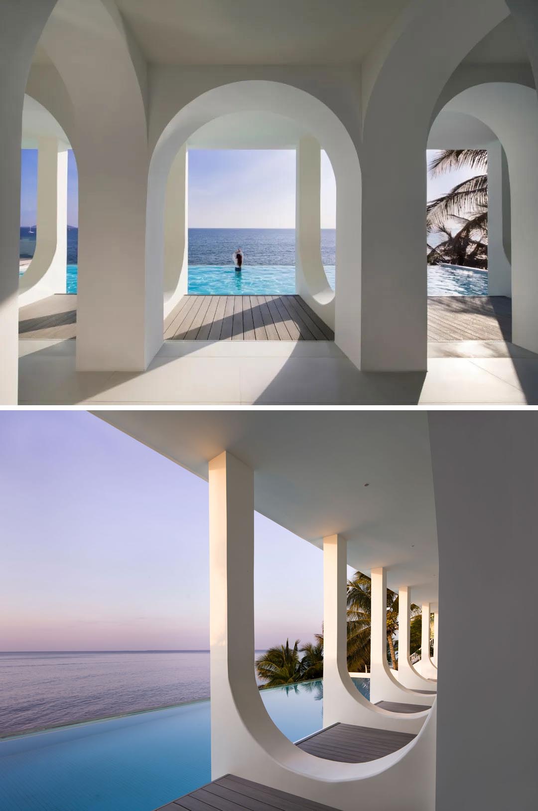 A modern white hotel includes an infinity edge swimming pool overlooking the ocean.