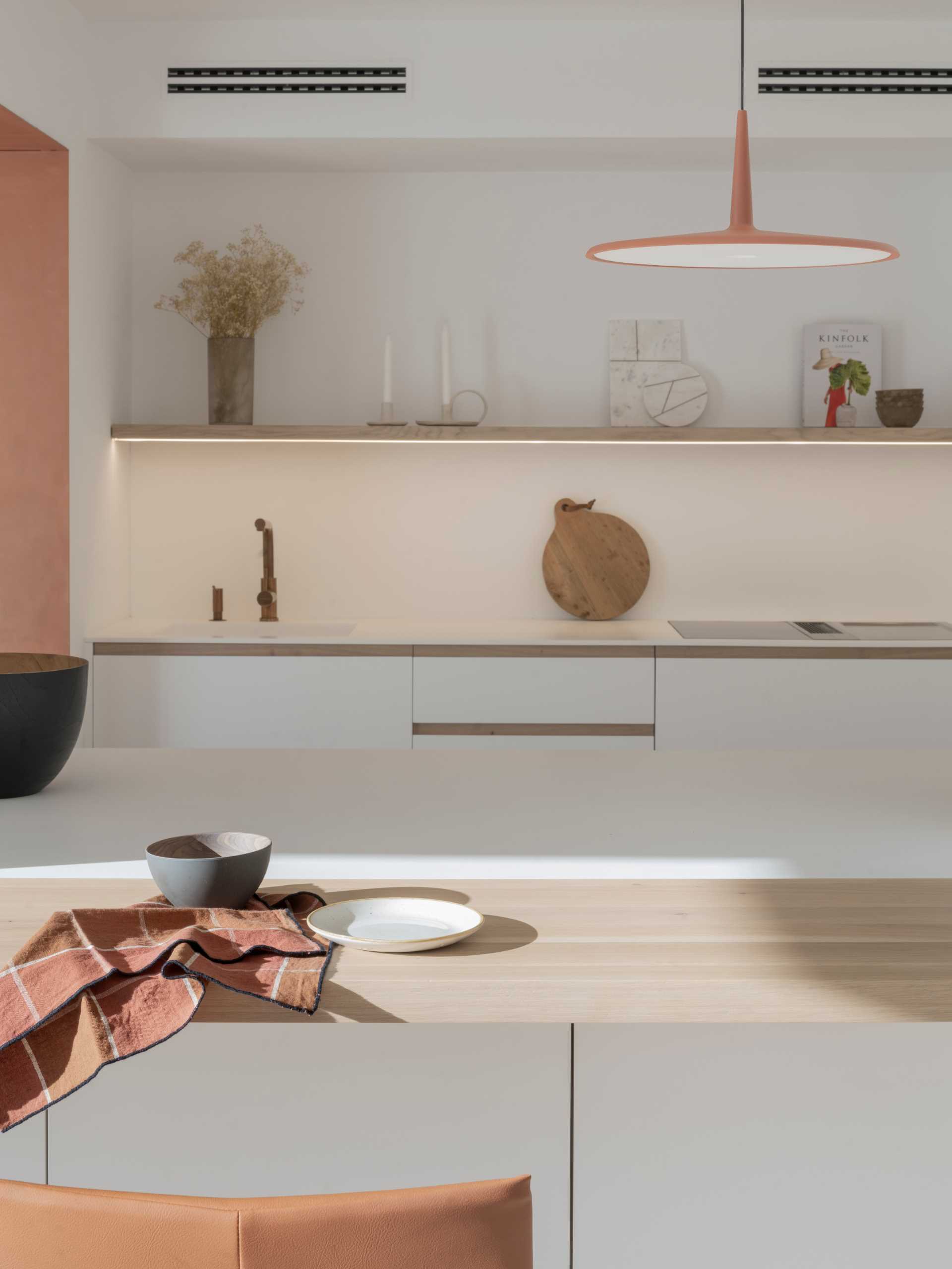 A modern white kitchen with wood and copper accents.