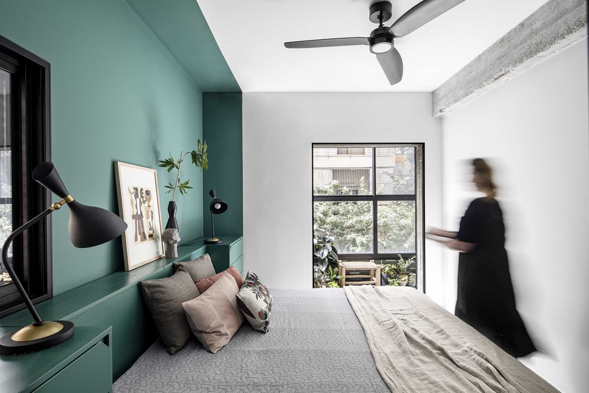 This modern bedroom has a green accent wall that frames the bed and wraps around the wall.