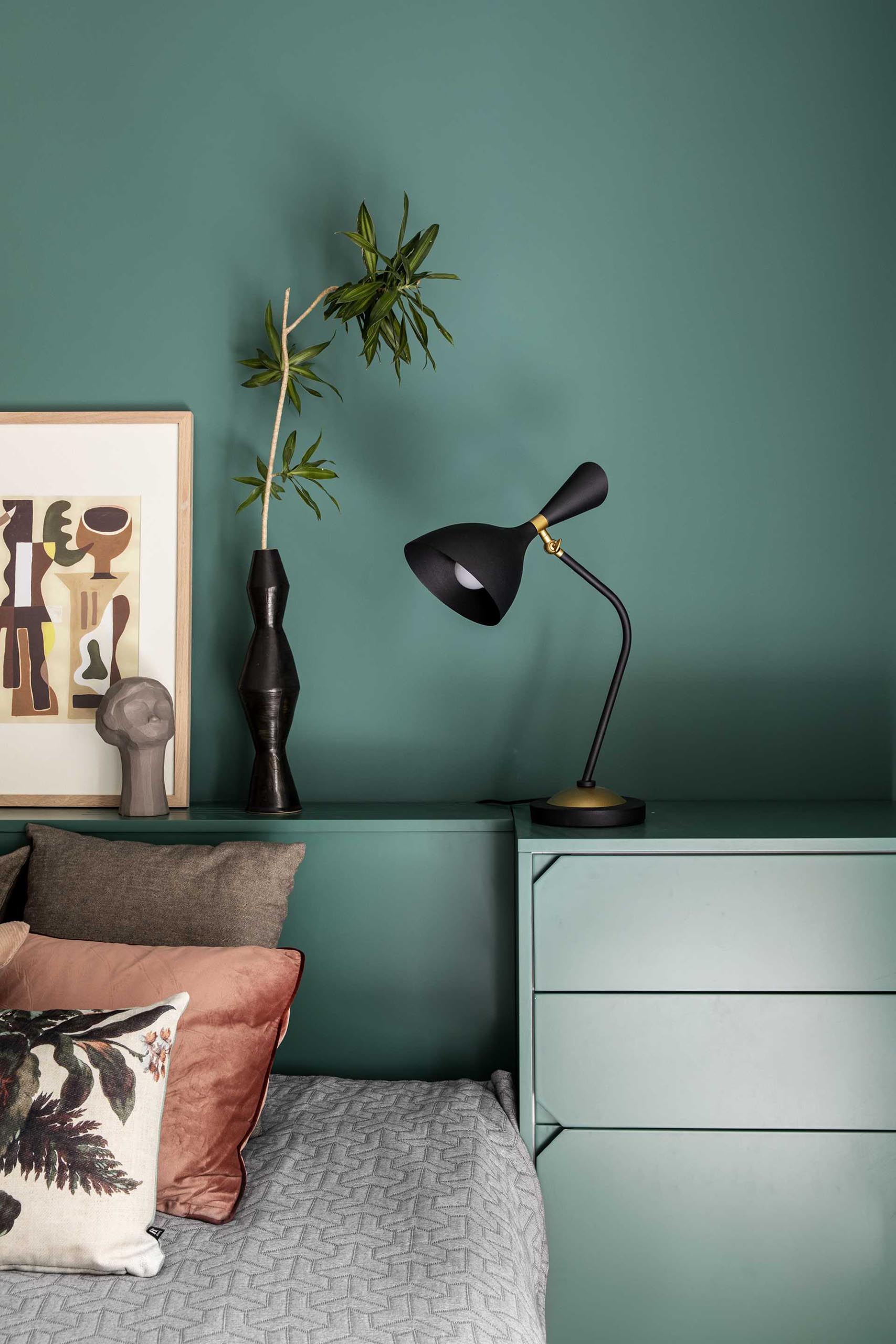 A modern bedroom with a green accent wall that frames the bed, headboard, and bedside tables.