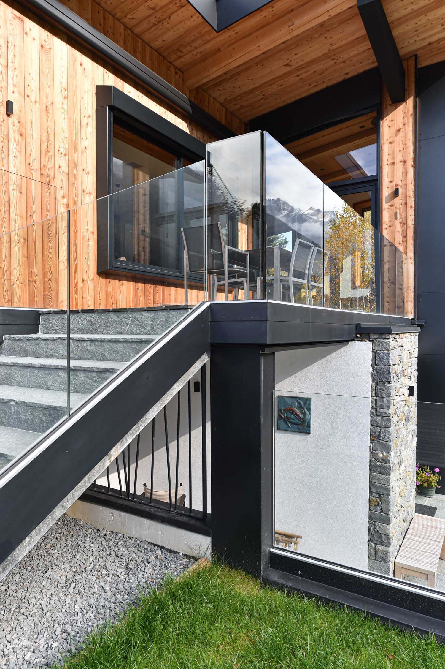 A modern home with wood siding, black accents, and glass railings.