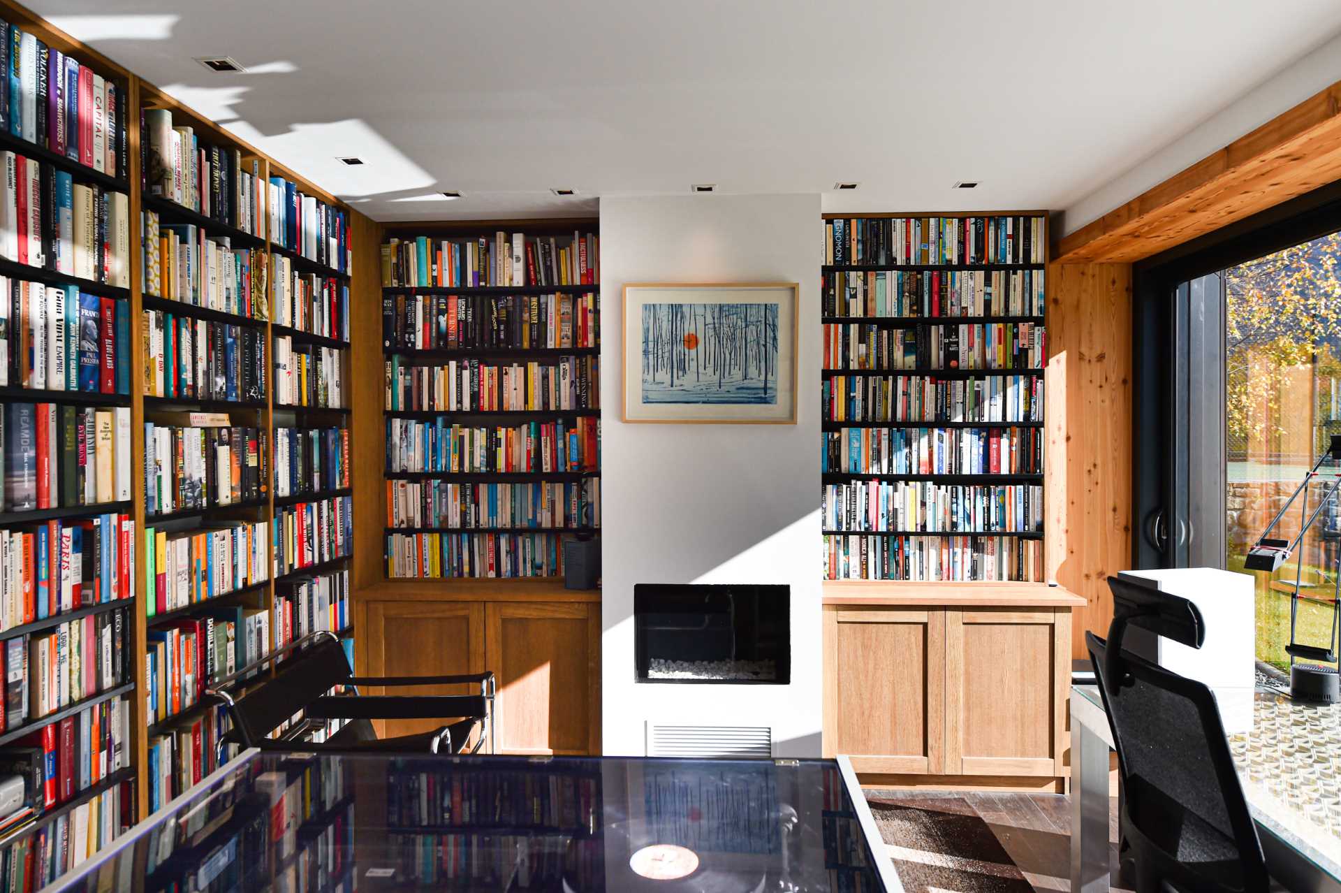 A home library with plenty of shelving, a fireplace, and a sliding glass door that opens to the patio.