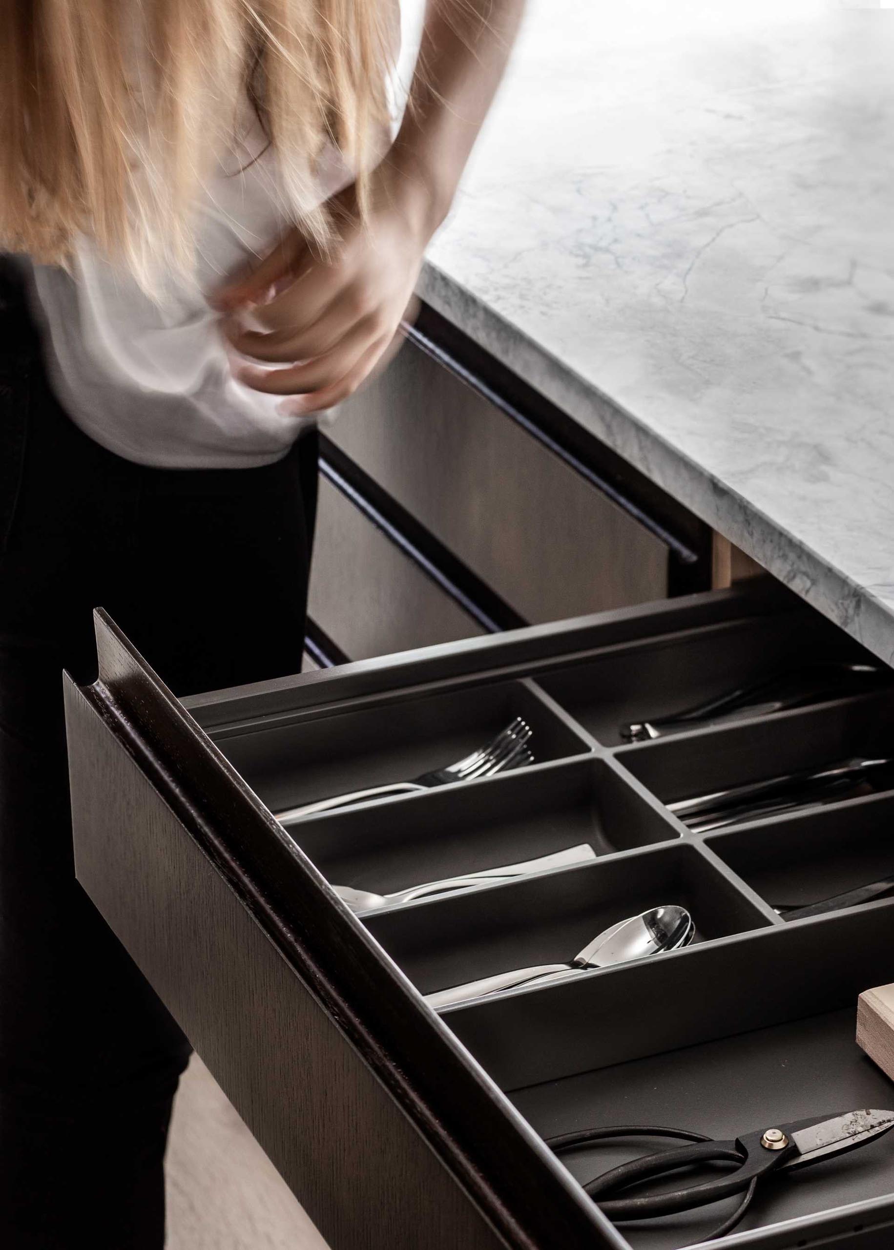 A modern dark wood kitchen with honed marble countertops.