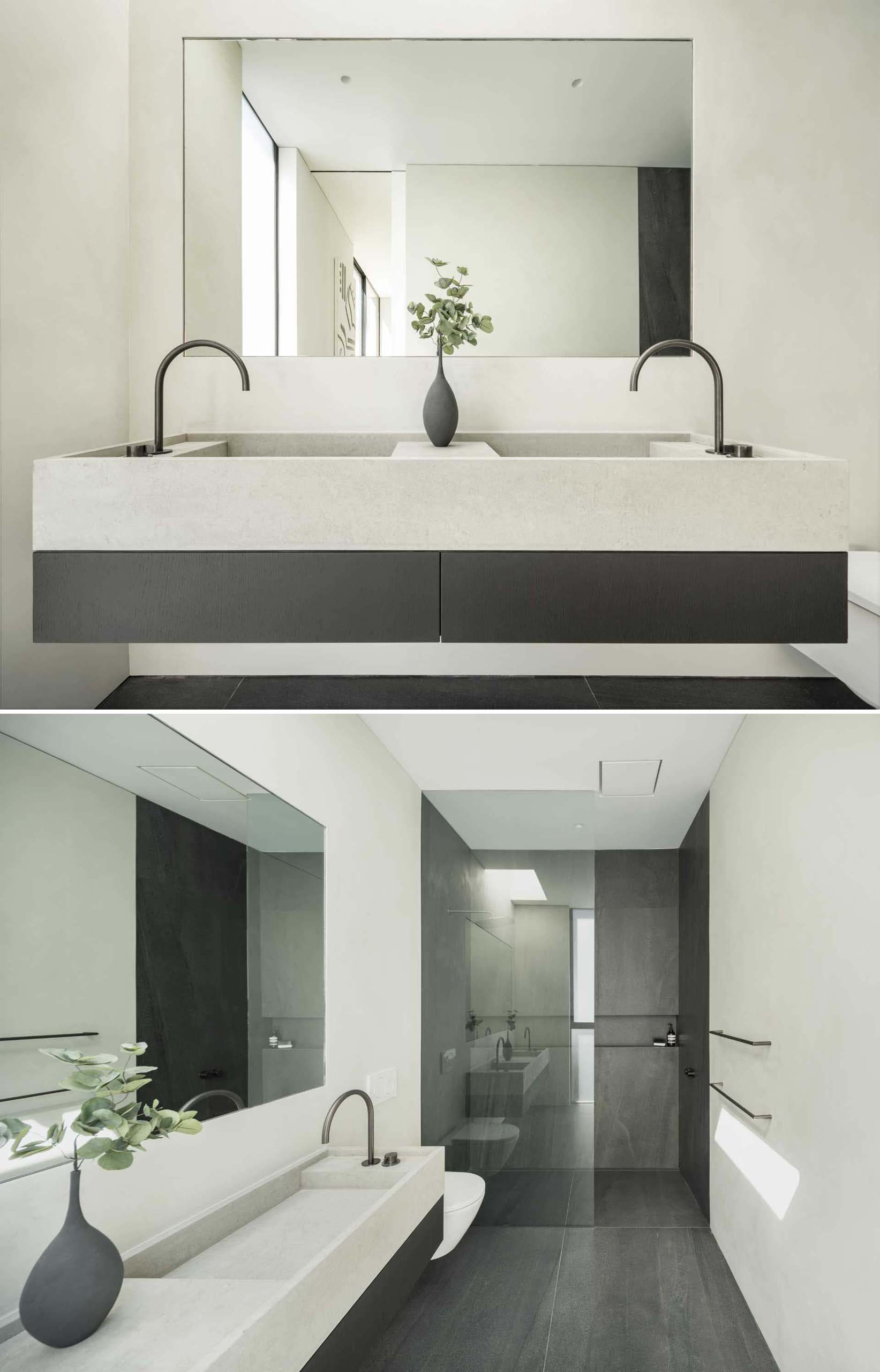 A modern bathroom with a a double vanity and a dark gray shower with a shelving niche.