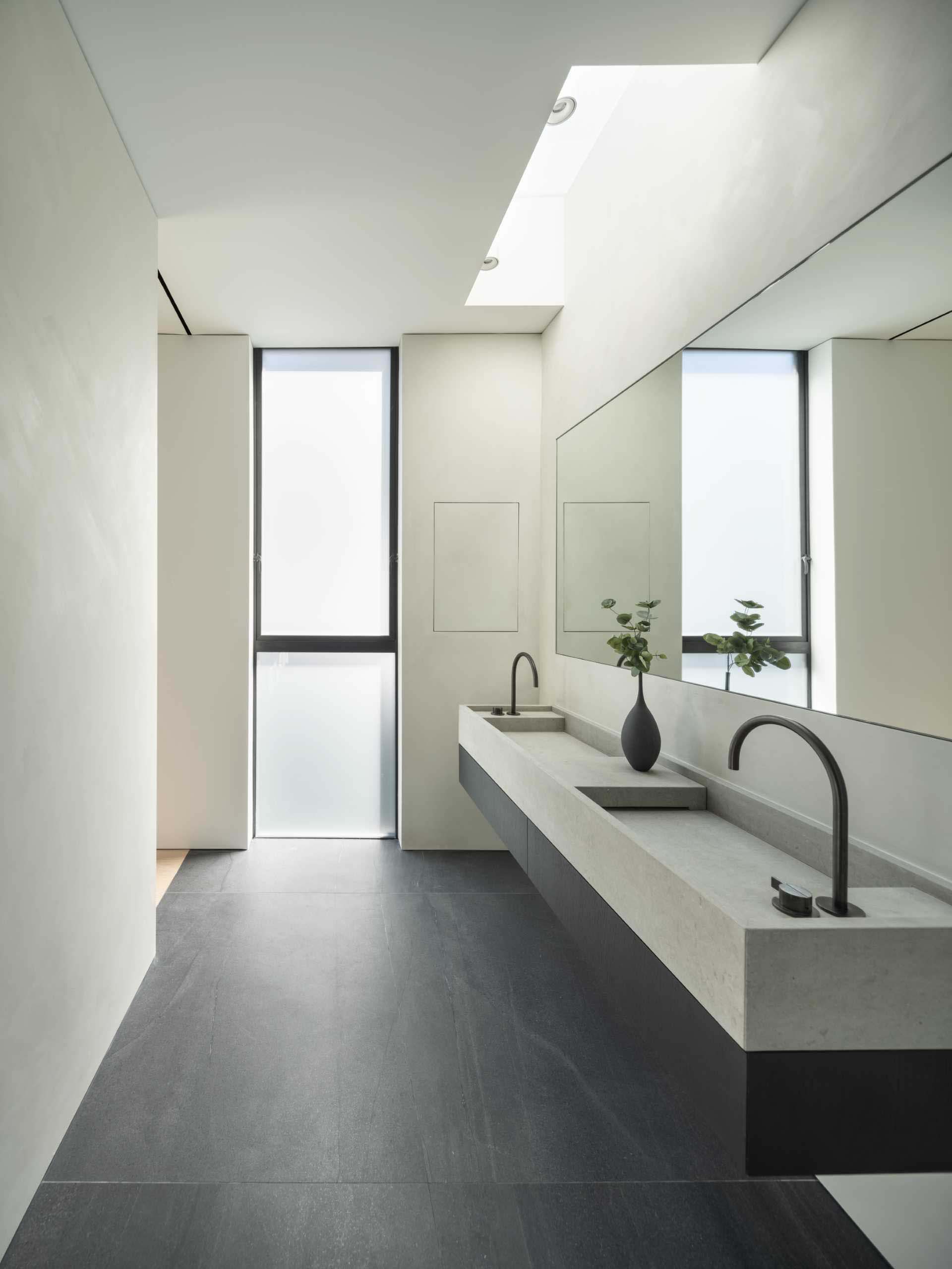 A minimalist bathroom with a double vanity and black tiled floor.