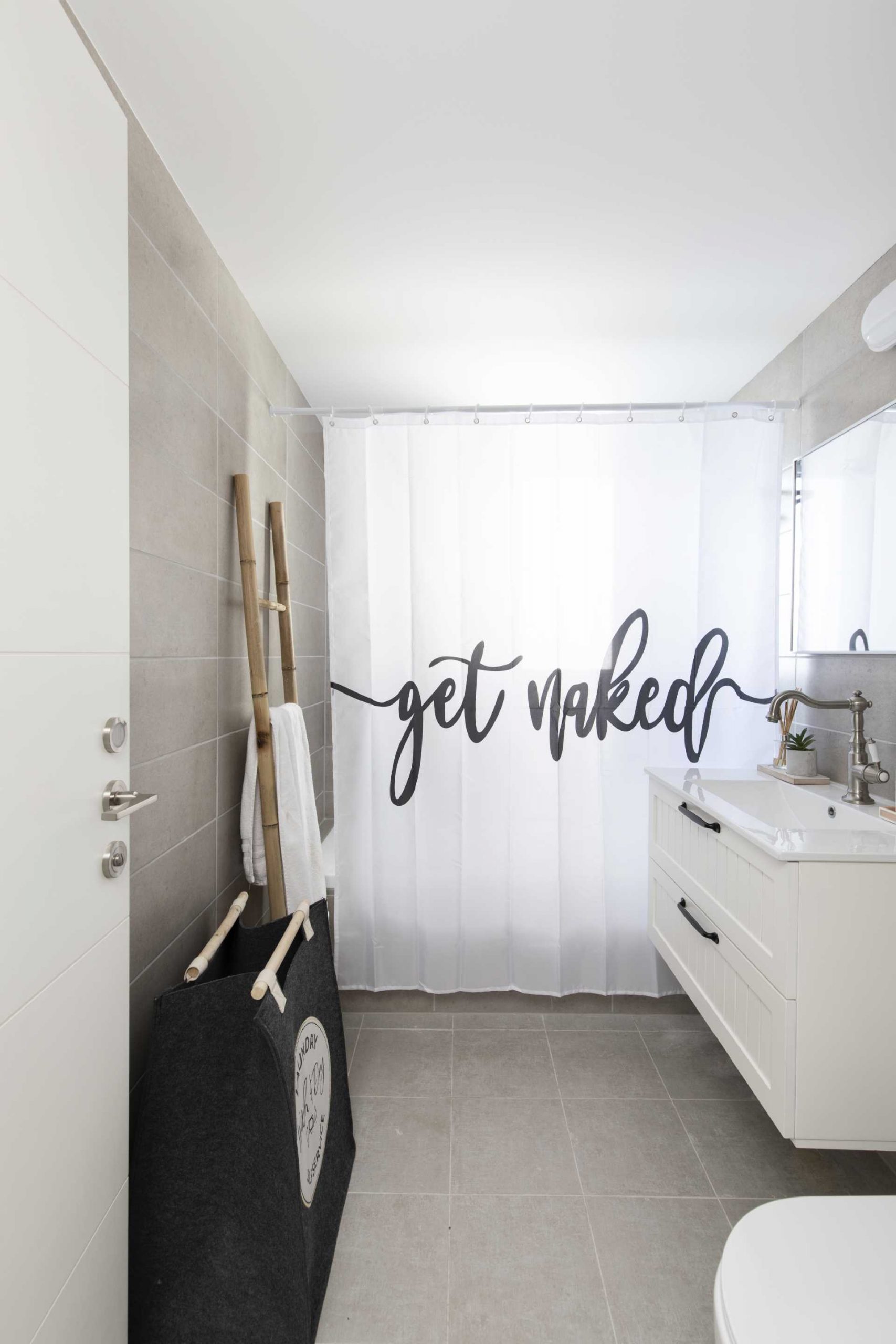 A modern bathroom with gray tiles and a white vanity.