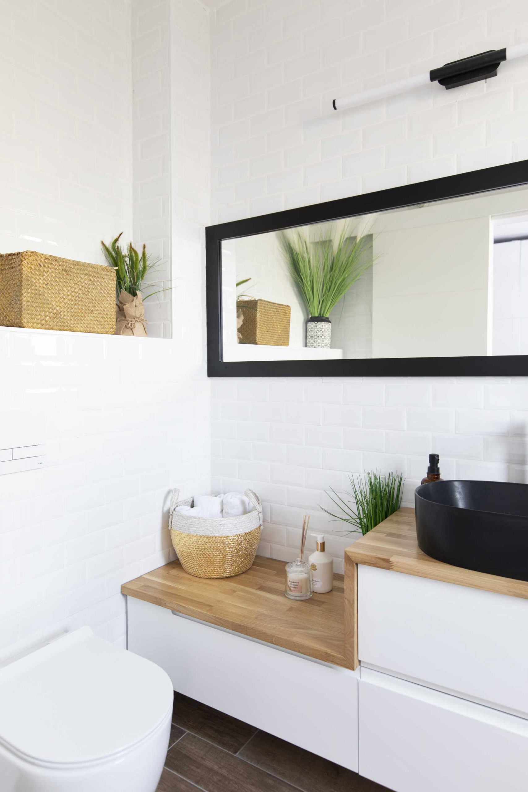 A modern bathroom with a white vanity, wood countertop, and black sink.