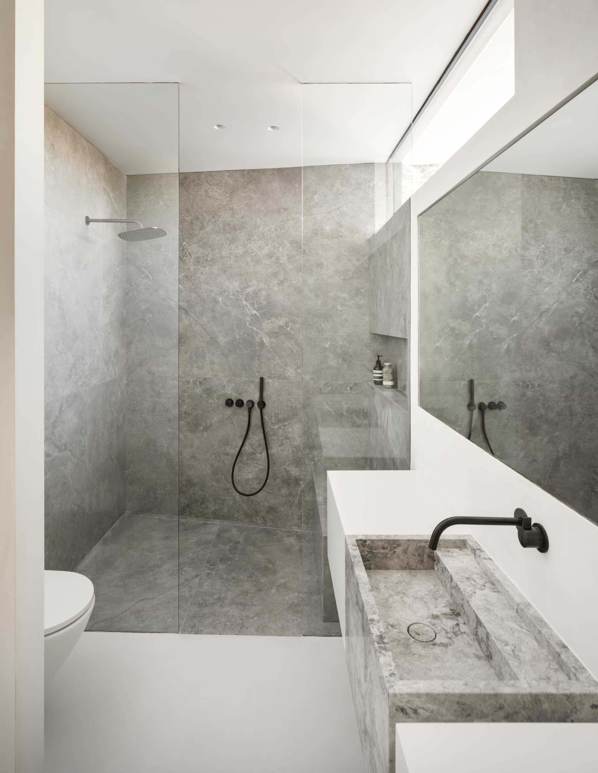 In this modern bathroom, there's a walk-in shower with a built-in bench and a secondary shelving niche.