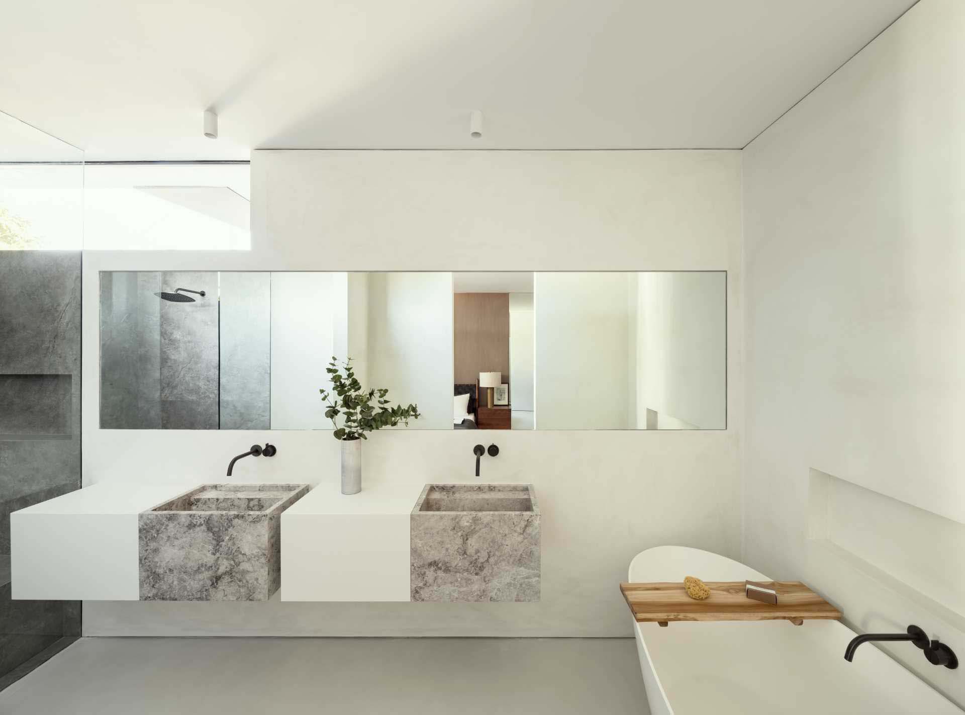 A modern bathroom with double vanity, a freestanding bathtub, a shelving niche, and a dark shower.