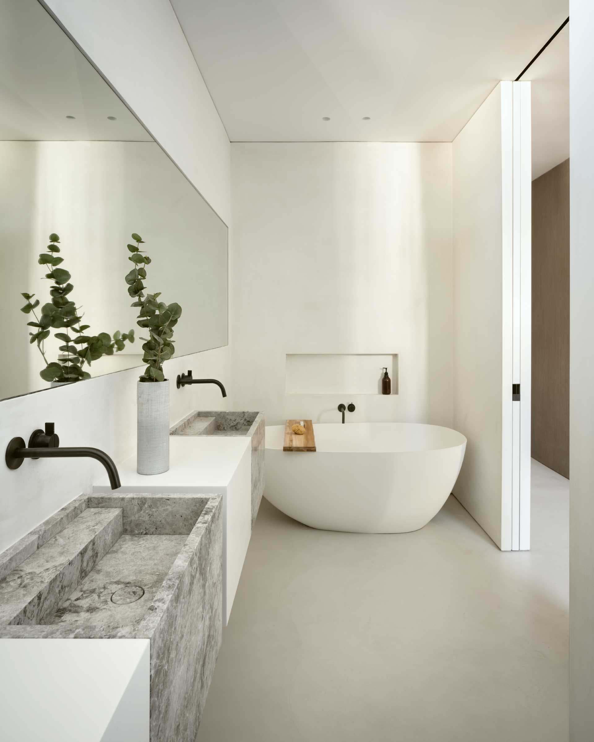 A shelving niche has been built into the wall adjacent to the freestanding bathtub in this modern bathroom, allowing for items like soap to be kept within reach.