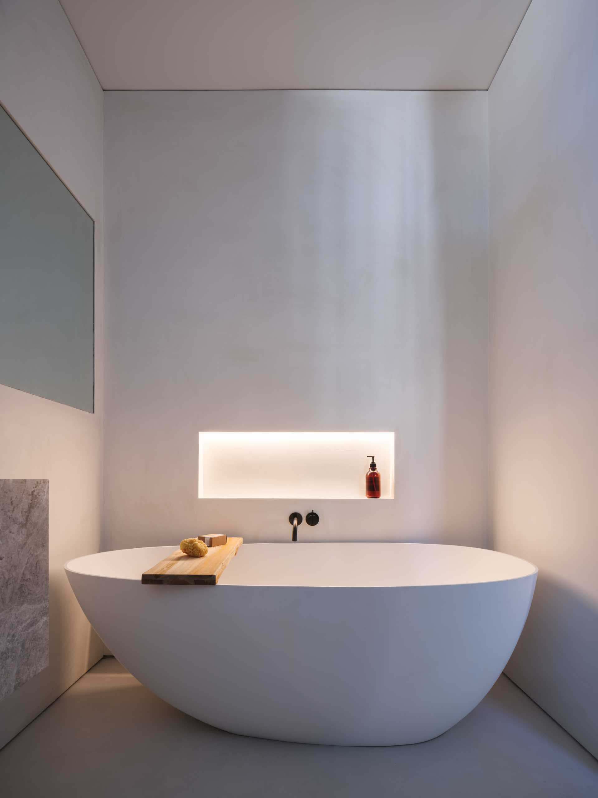 This modern bathroom has a shelving niche by the bathtub. Hidden LED lighting has been included, which when turned on, creates a soft glow and adds to the calm atmosphere of the bathroom.