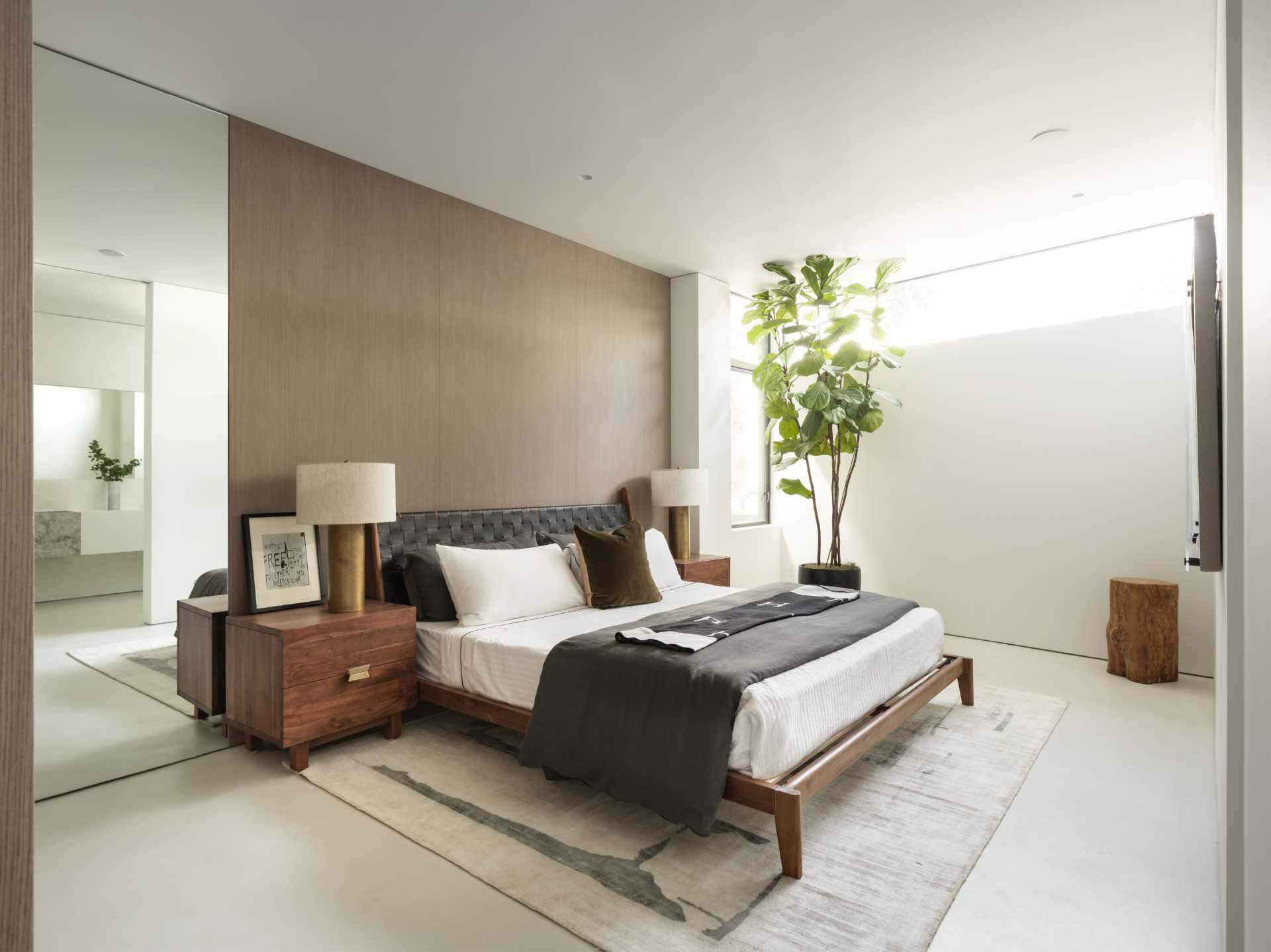 A modern bedroom with a wood accent wall and a high window.