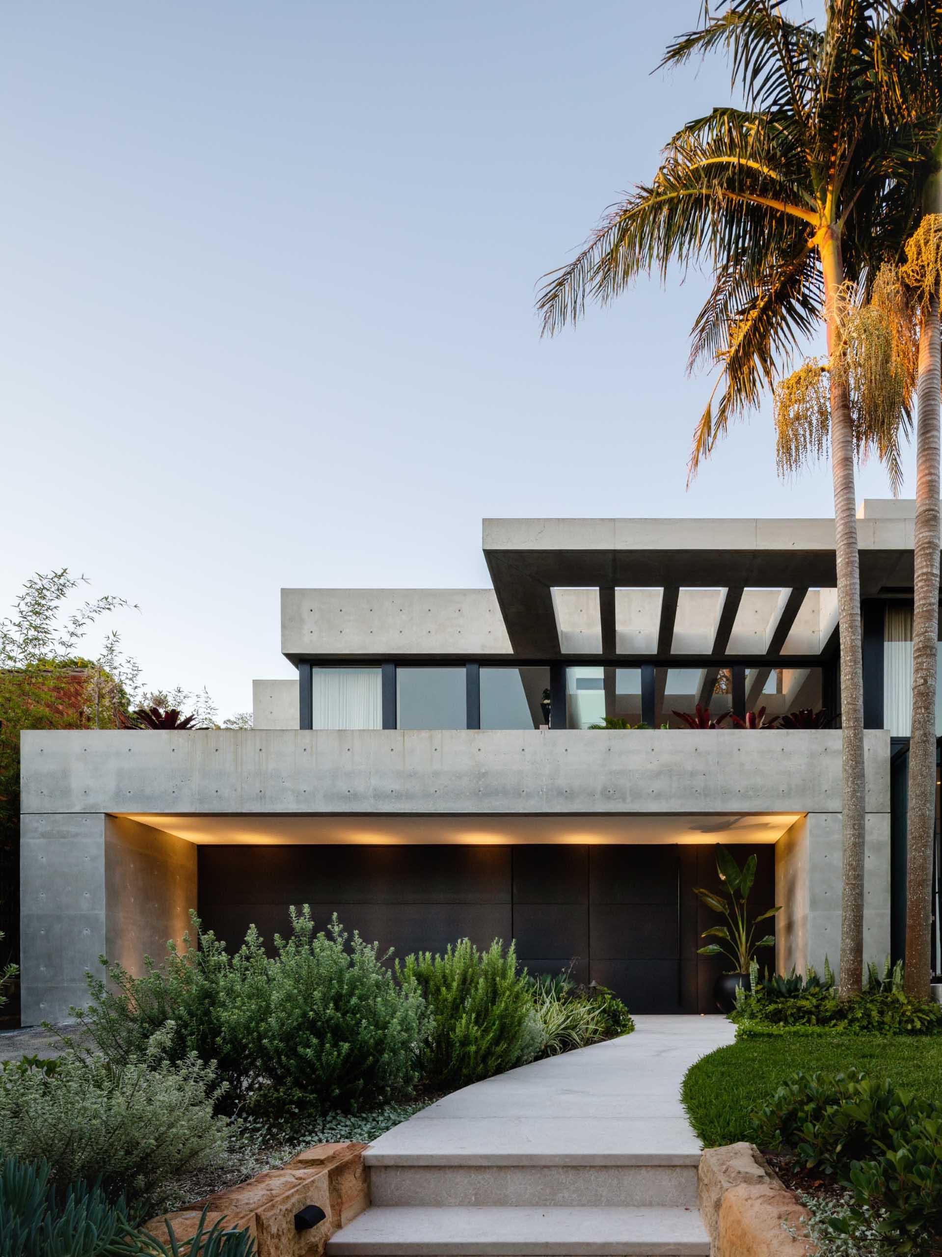 A modern home with a path the winds its way to the covered front door.