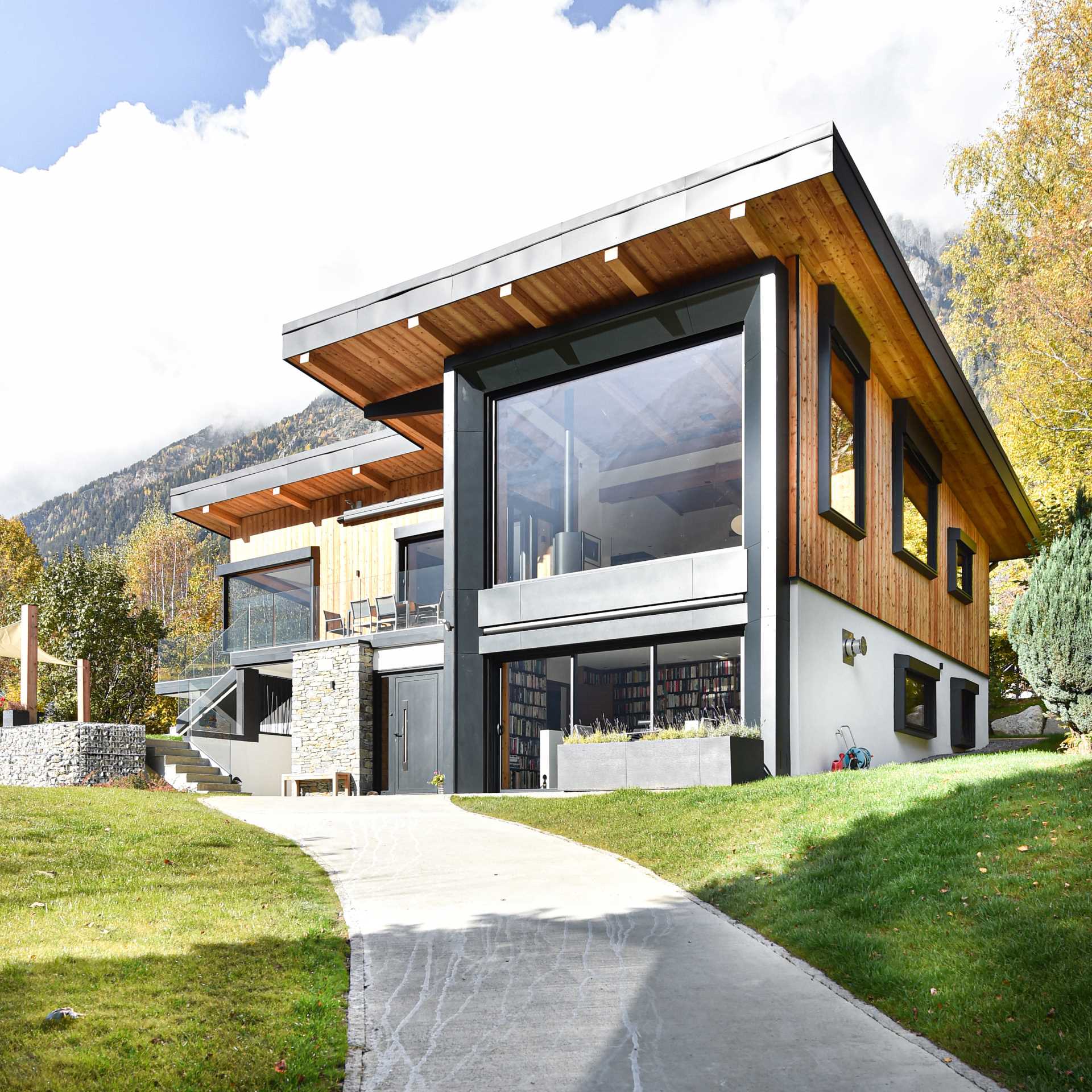 A modern house that features a large picture window that looks out onto the surrounding area.