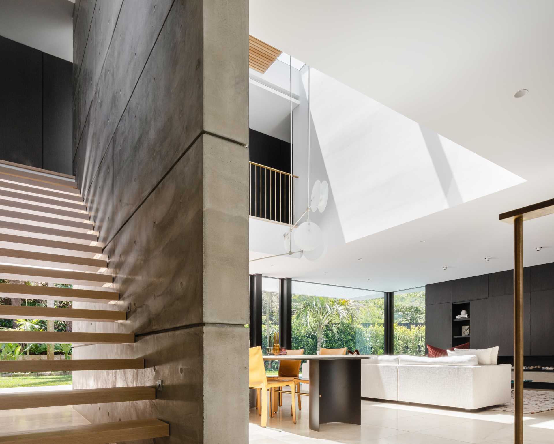 A modern house with concrete walls, limestone tiled flooring, and wood stairs.