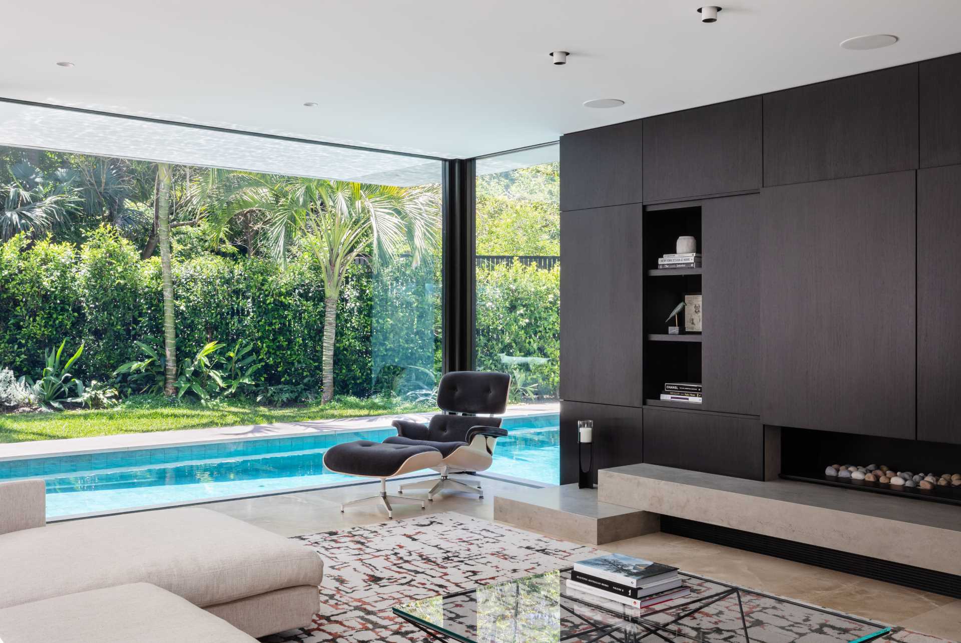A modern living room with floor to ceiling windows and views of the pool.