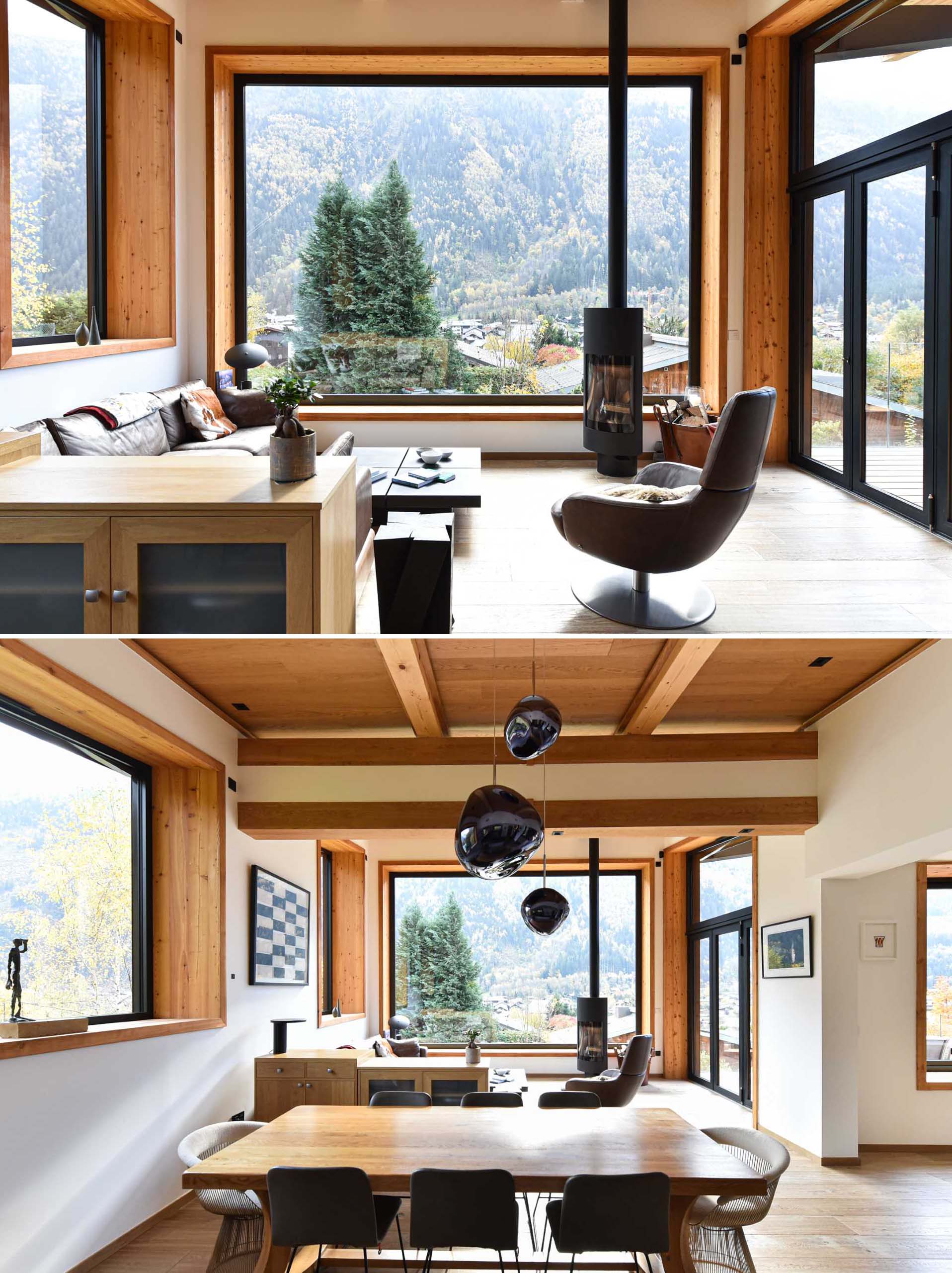 A living room with a fireplace and a large picture window that perfectly frames the view of the neighbouring houses, as well as the trees and nearby mountain.