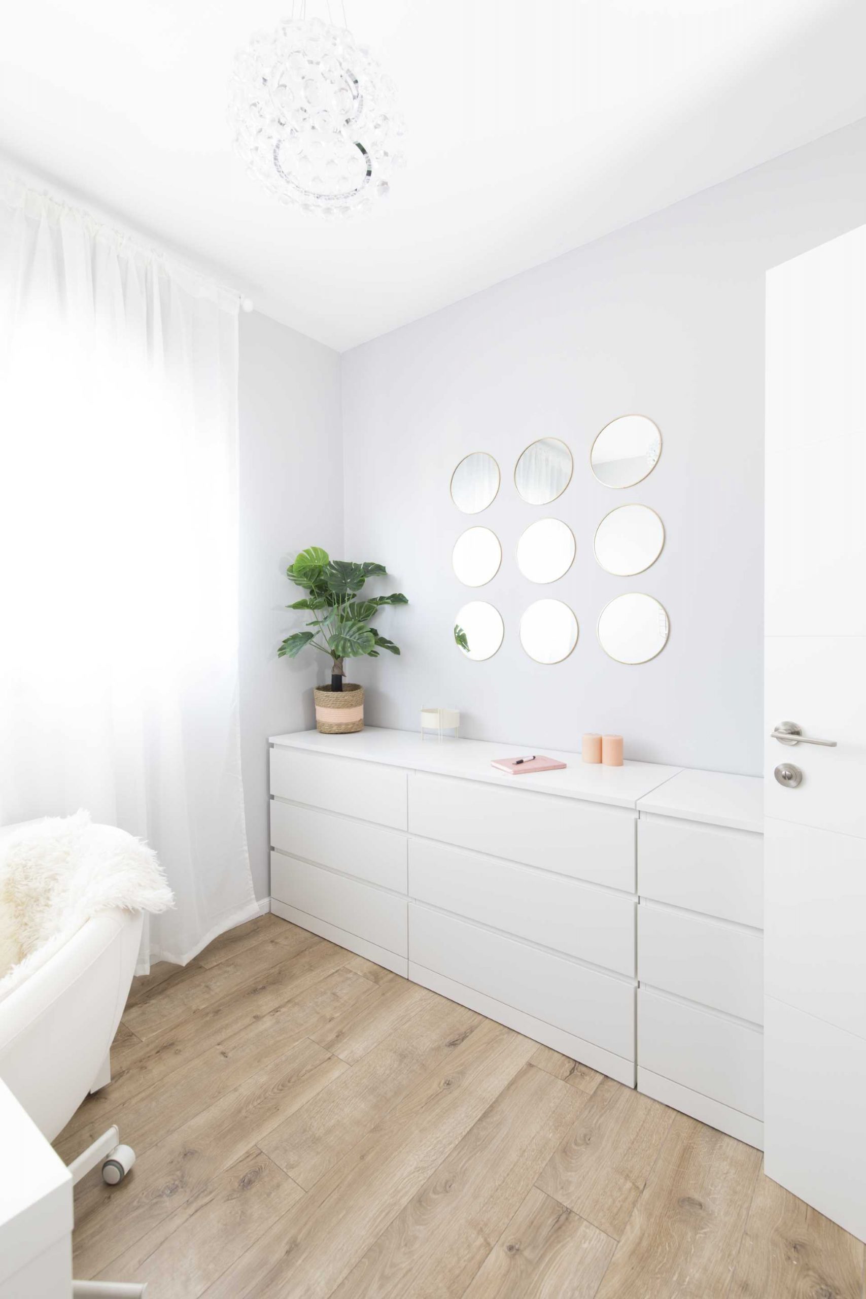 In this modern home office, there's light gray walls, a white cabinet, and wood floors.