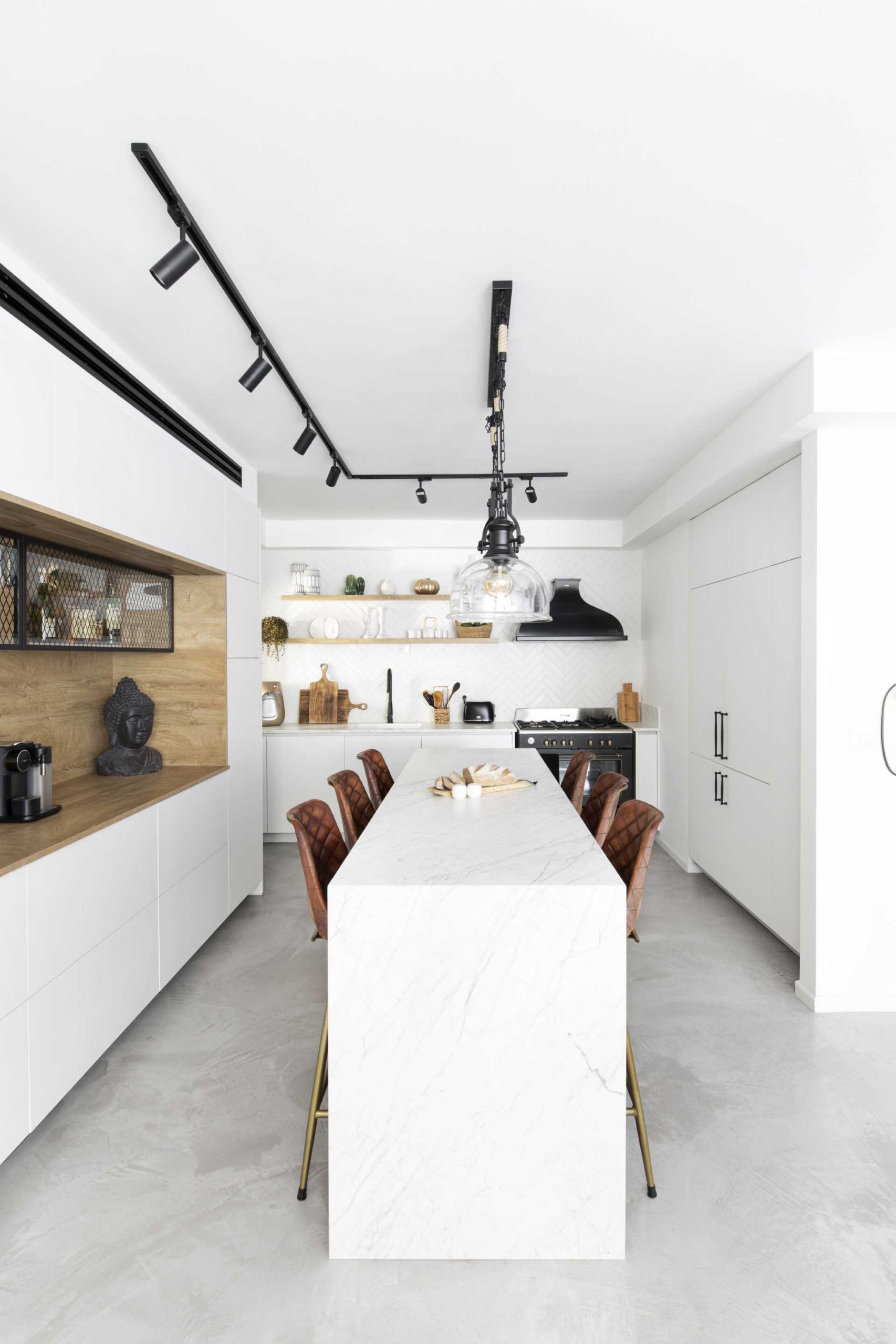 A modern white kitchen interior with wood and matte black design elements, includes an island that double as a dining table.