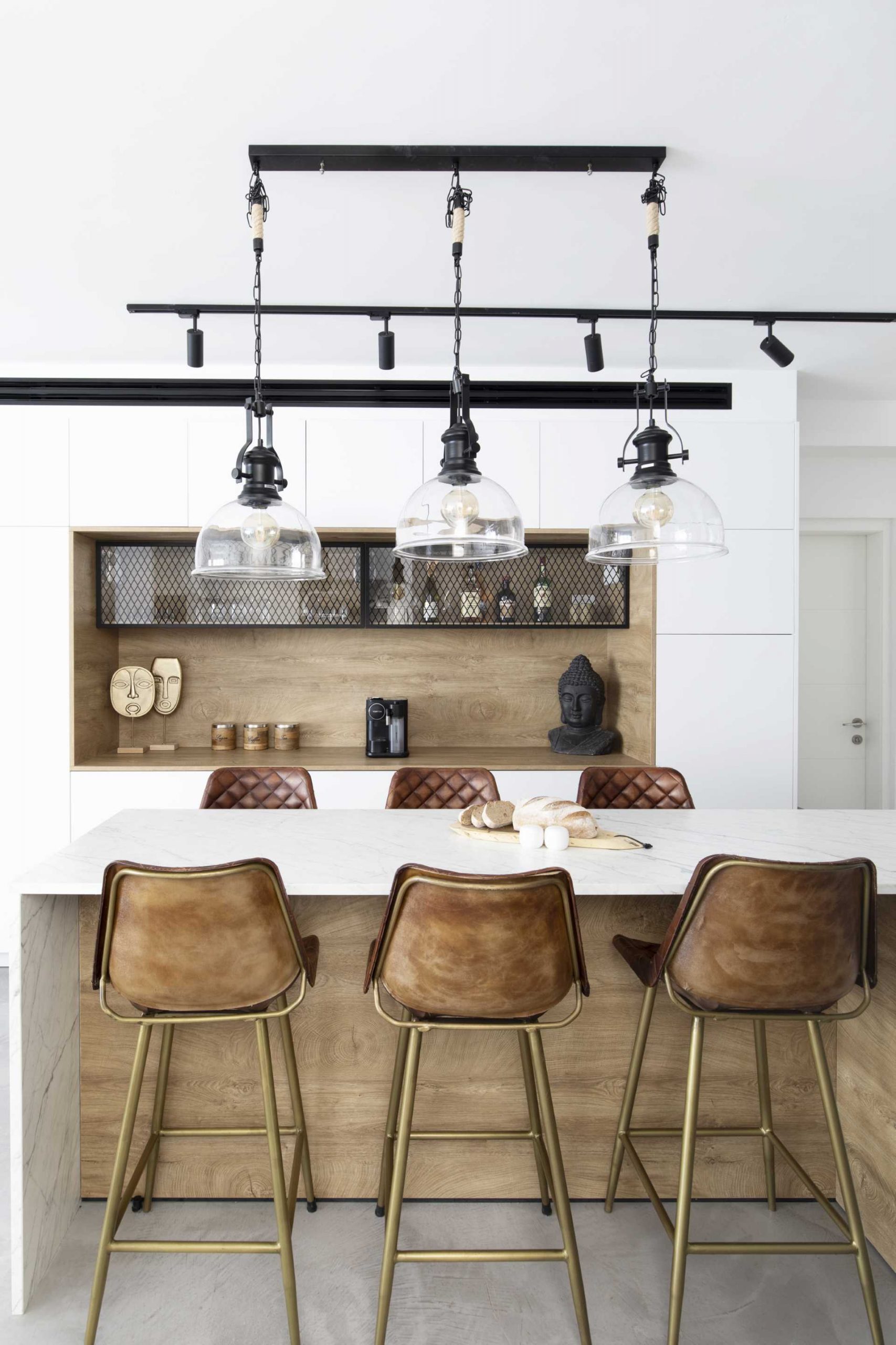 A modern kitchen with wood and matte black design elements, includes an island that double as a dining table.