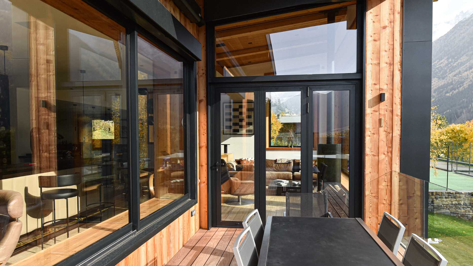 A modern home with wood siding, black window frames, and outdoor dining area.