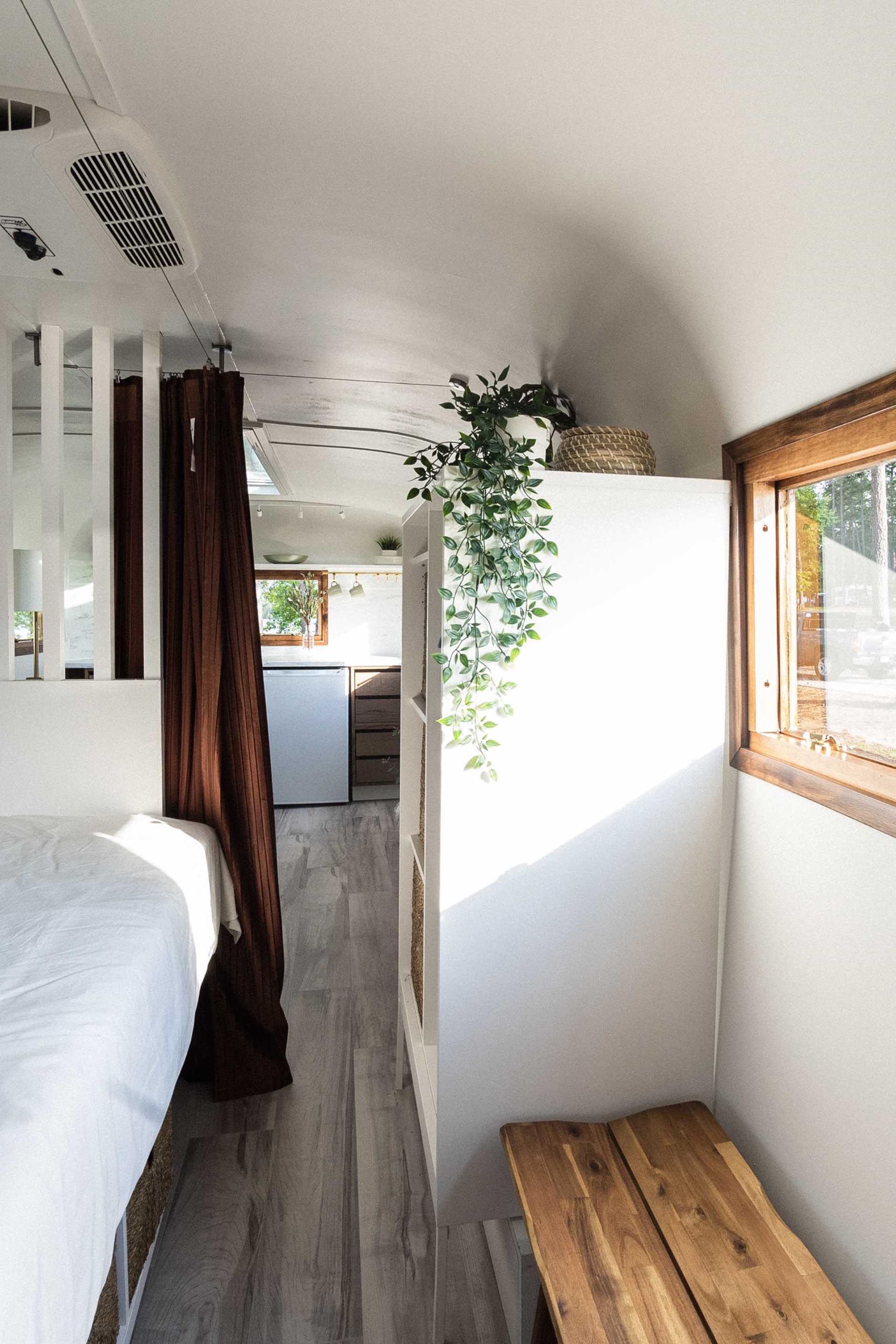A renovated vintage travel trailer includes a raised bed with storage underneath and built-in bookshelves.