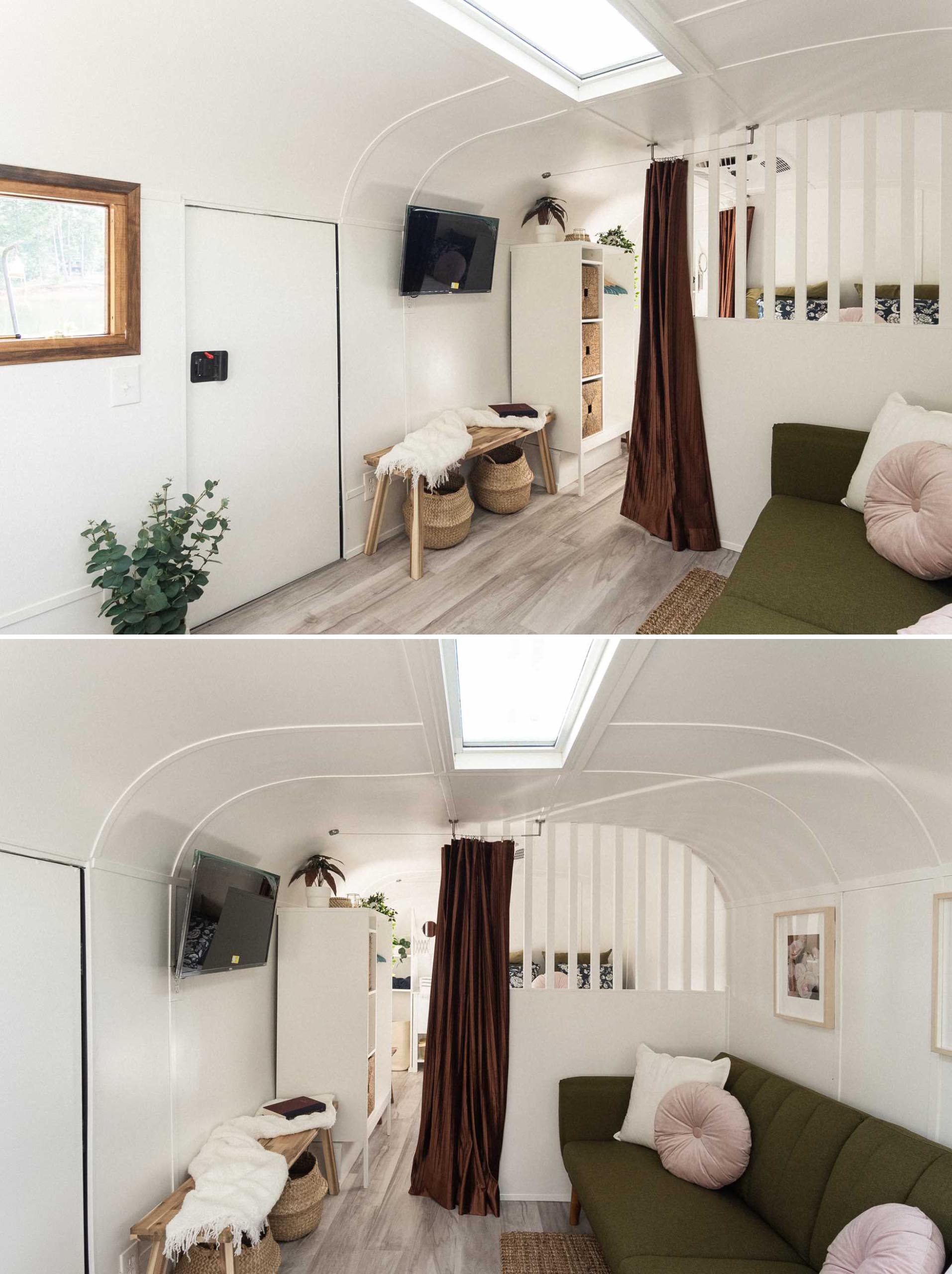 The entryway of this remodeled vintage travel trailer includes a bench with a couple of storage baskets, and a wall-mounted tv.