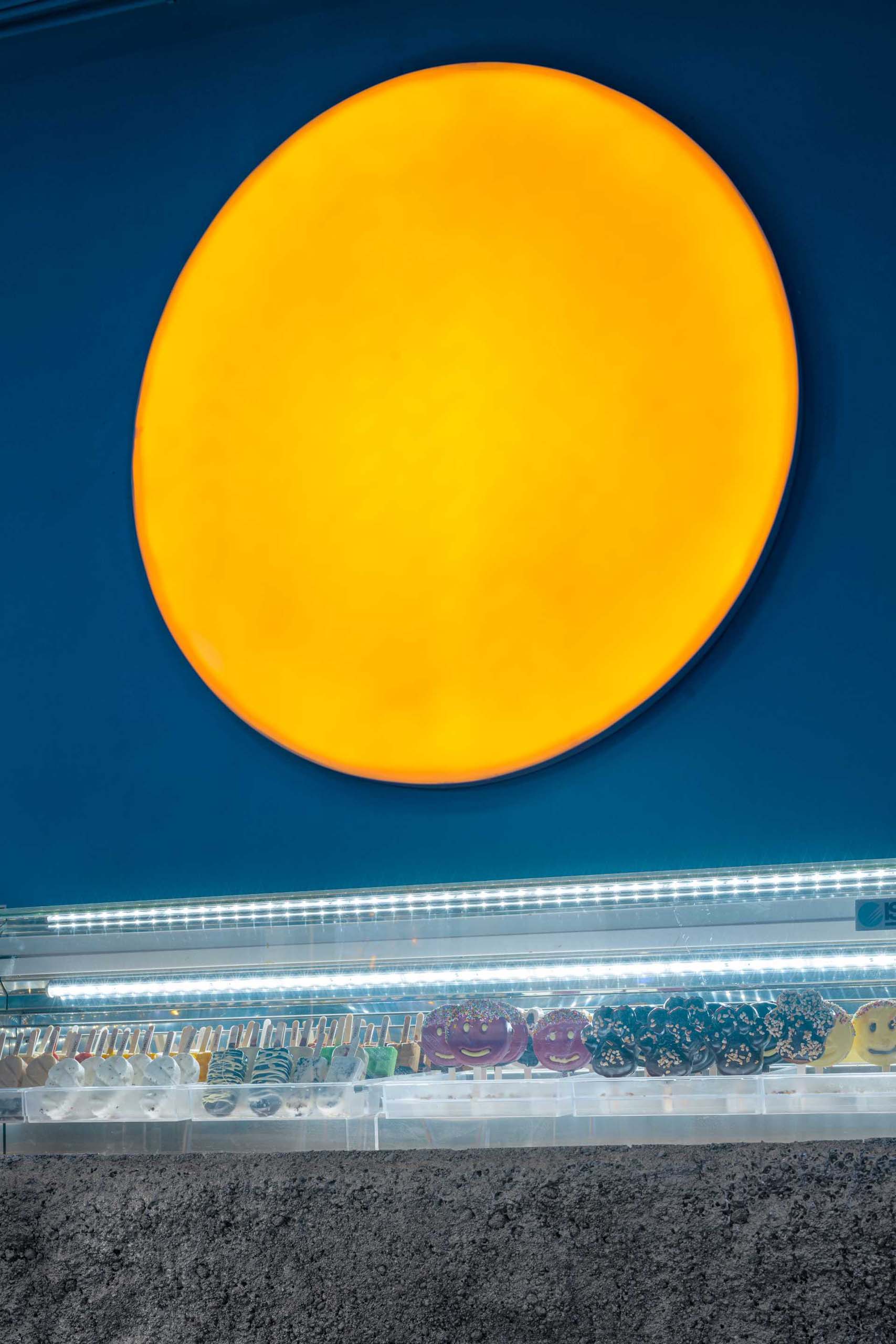 A large round light with an orange glow is a bright accent to the all-blue wall.