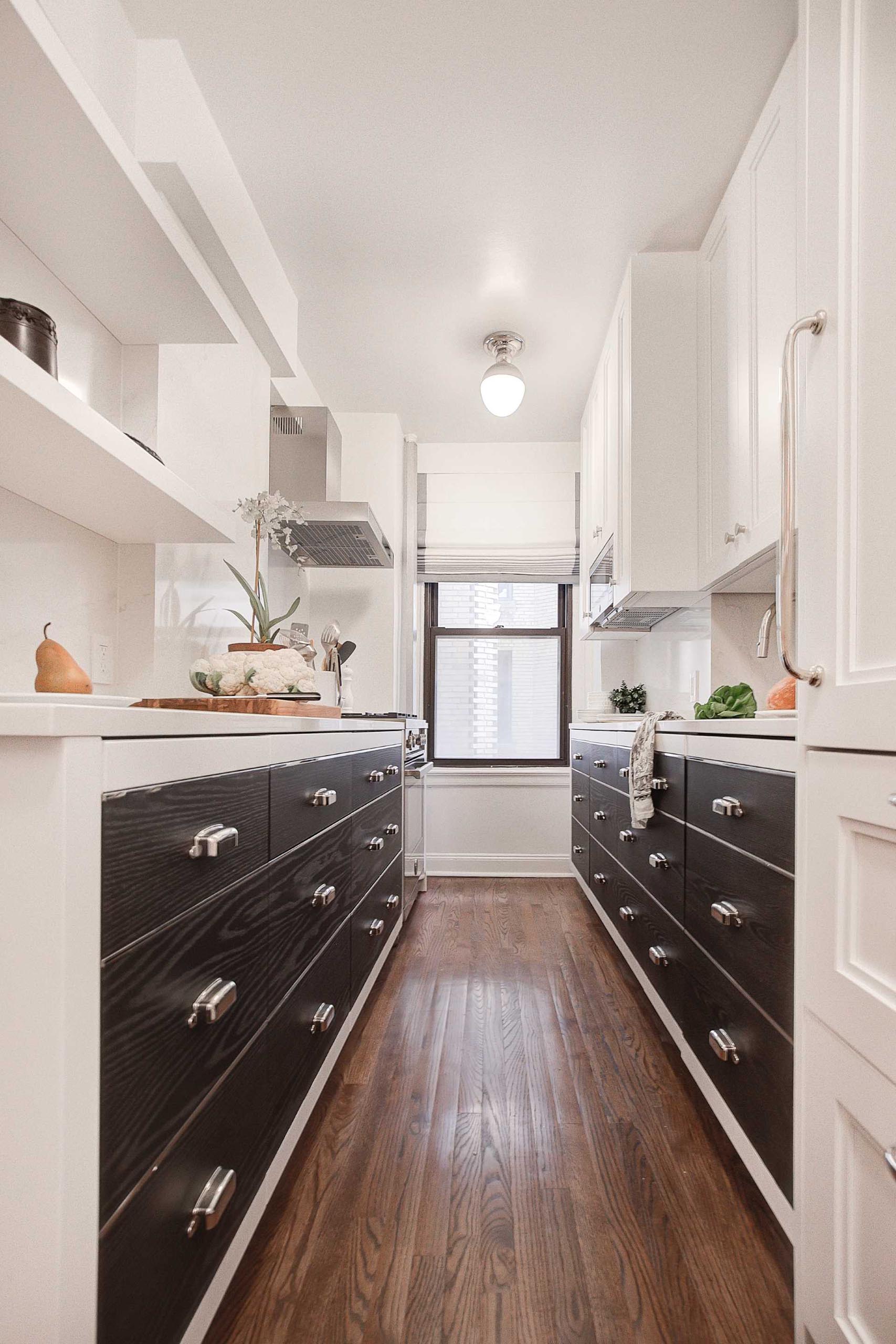 A contemporary kitchen with black and white cabinets, and wood flooring.