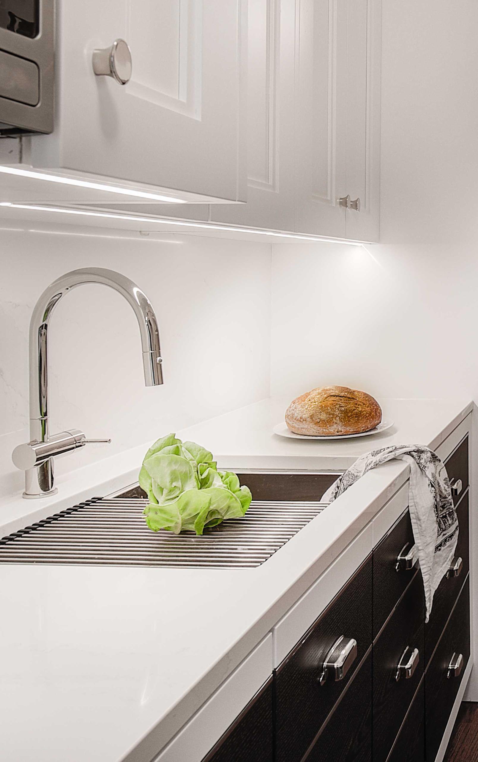 A contemporary kitchen with a stainless steel sink and drying rack.