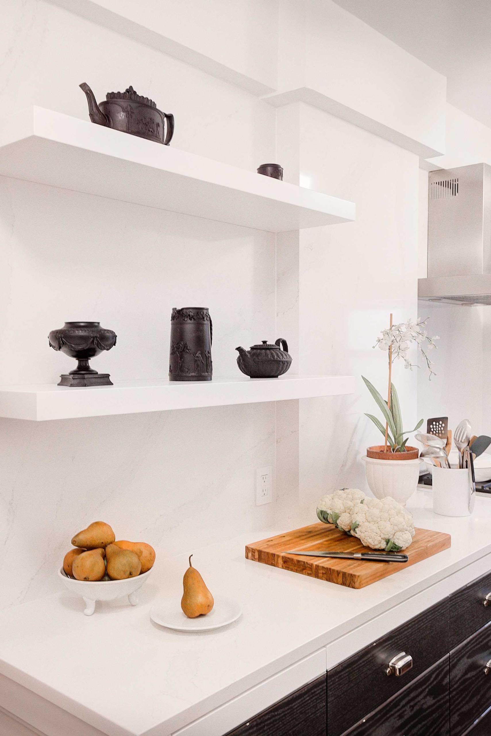 A contemporary kitchen with a pair of floating shelves that almost blend into the wall.