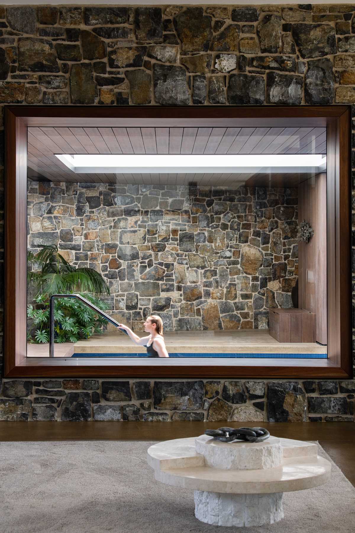 A window in the living room provides a view of the cantilevered pool that travels from the interior to the exterior of the home