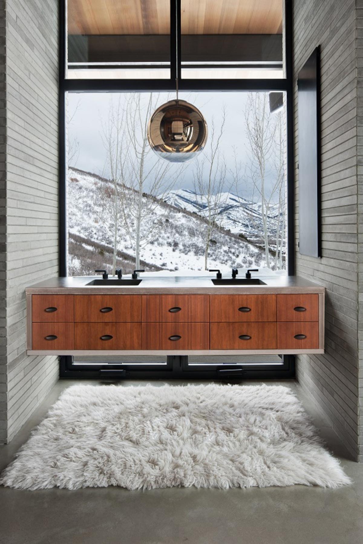 In this modern bathroom with cut limestone walls, a floating wood and concrete vanity has been positioned in front of the large window, maximizing the views.