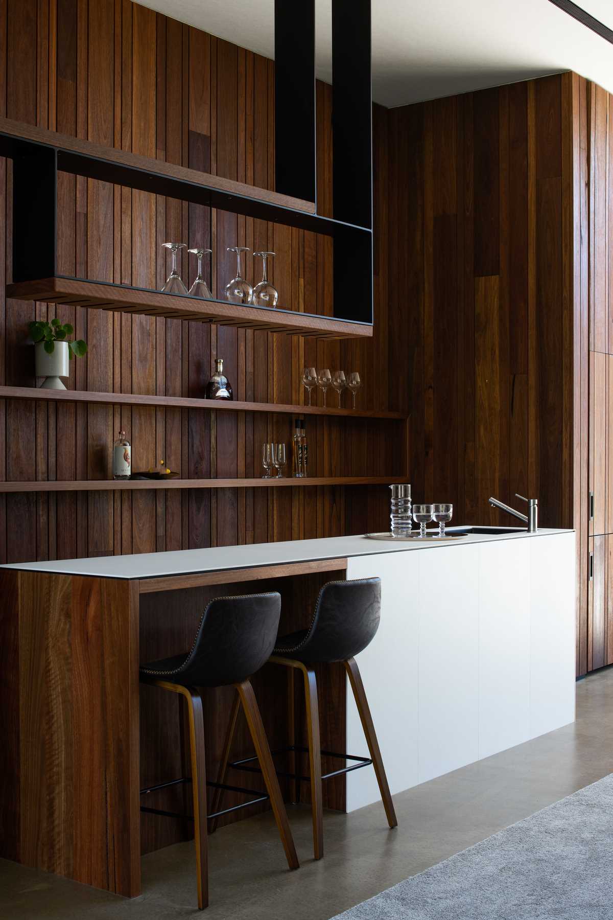 A modern games room with a bar and rich wood accent wall.