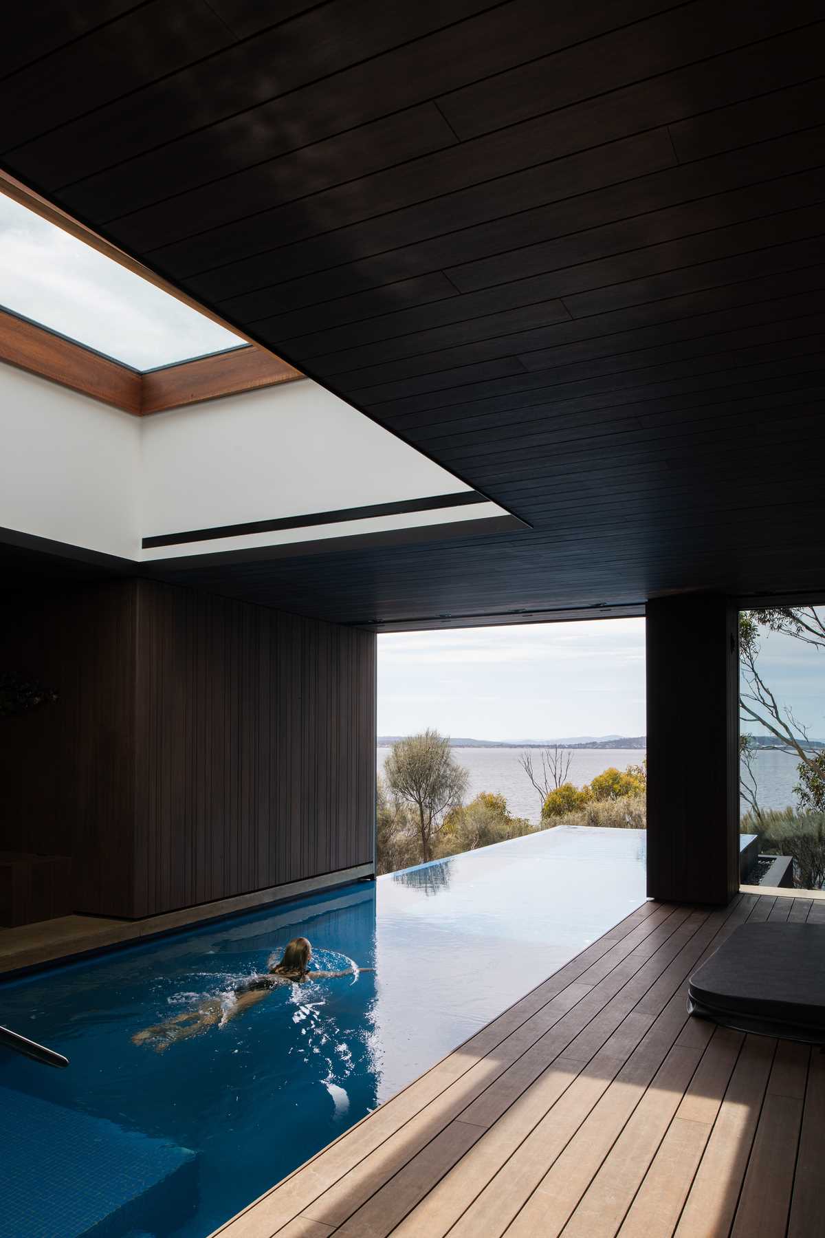 A modern swimming pool that travels from the interior to the exterior of the home.