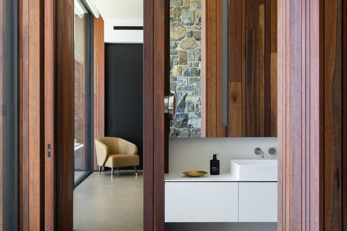 A modern bedroom and bathroom with stone and wood walls.