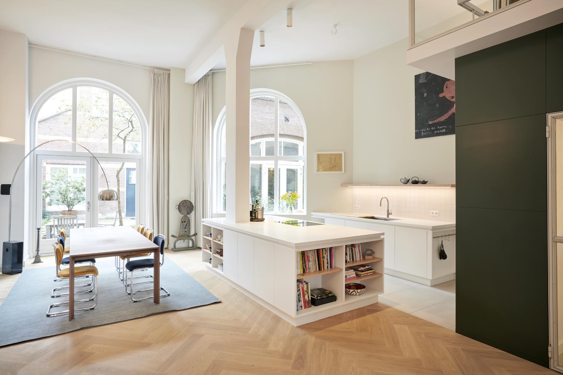 A modern white kitchen with an island that incorporates a tall column.