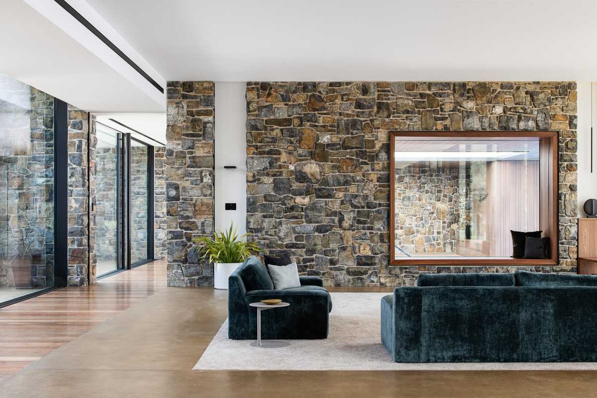 In the living room, the caramel burnished concrete floors are visible, complementing the nearby wood flooring and the colours found in the stone walls.