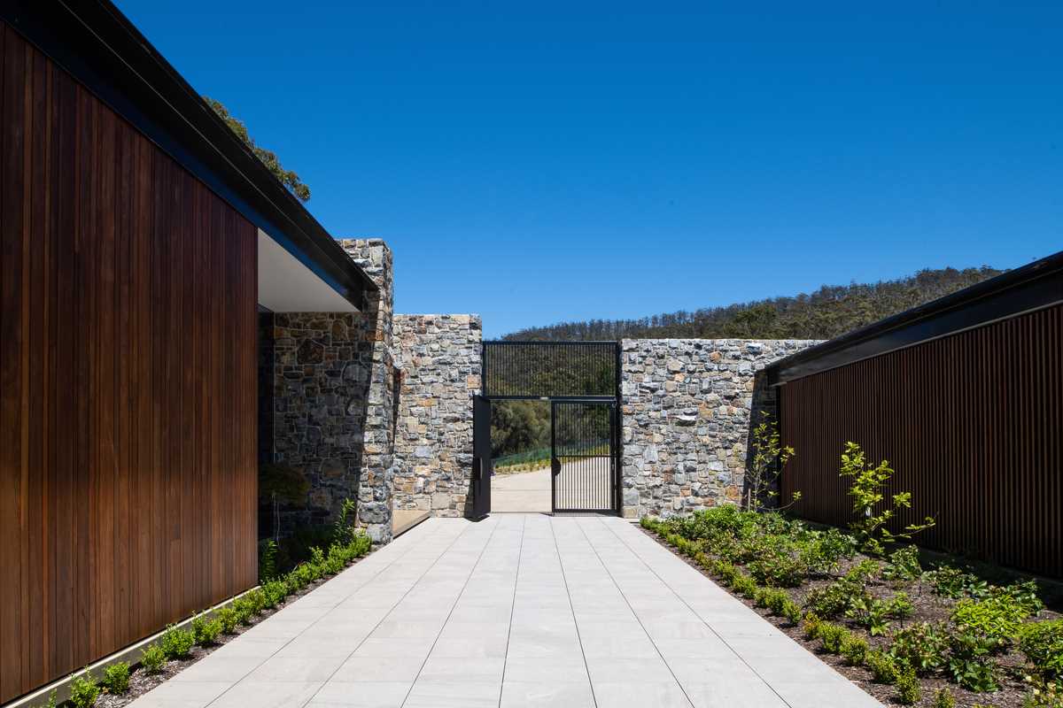 The entry gate opens up to a courtyard with low ground cover and a wide pathway.