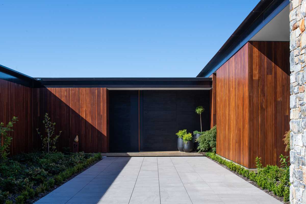 An oversized pivoting door has a black finish that ties in with the black steel details of the home.