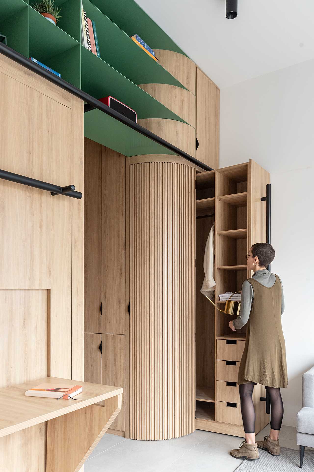 A hidden closet in this small apartment slides out to reveal drawers, shelves, and an space to hang clothes.