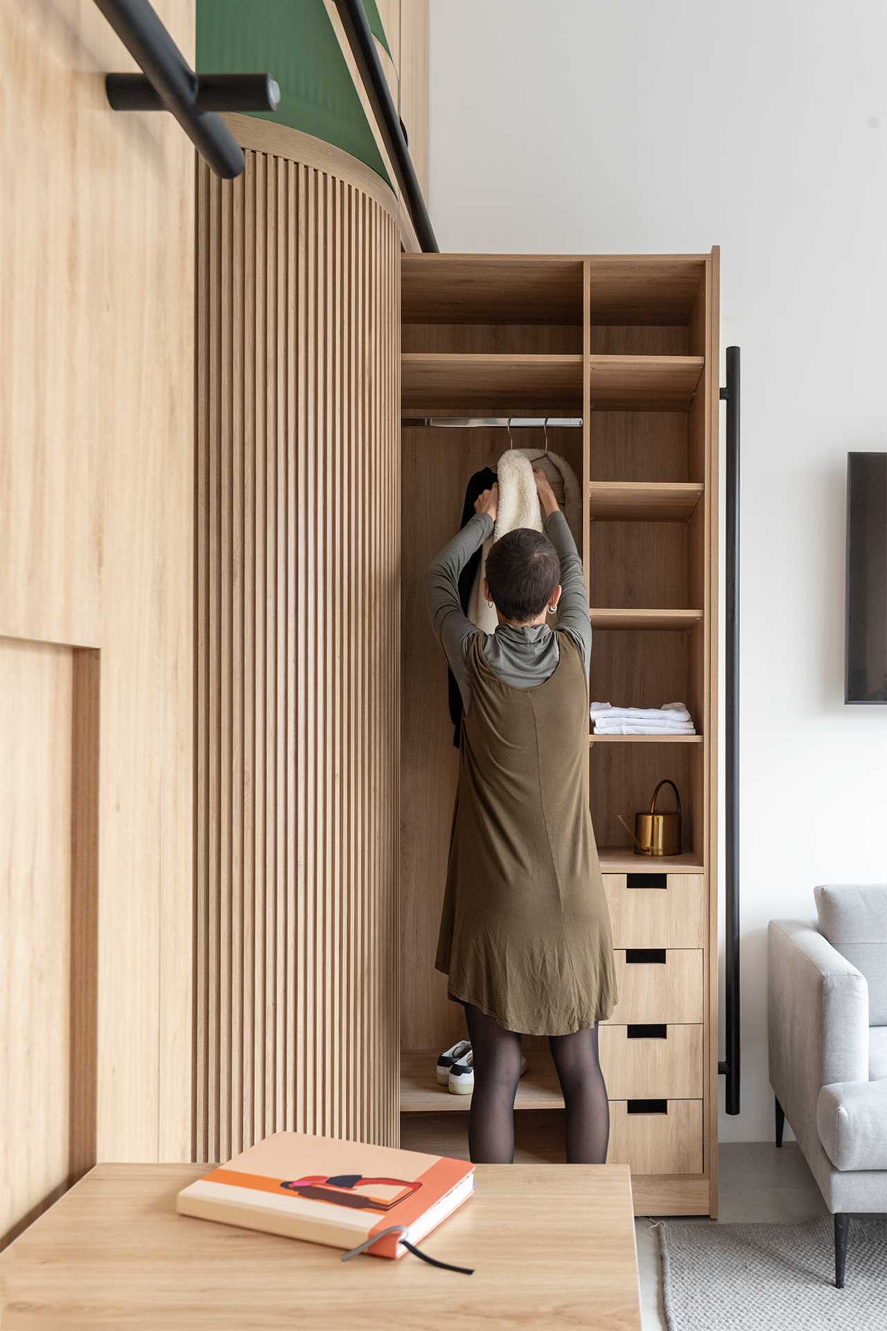 A small apartment includes a hidden closet that slides out to reveal drawers, shelves, and an space to hang clothes.