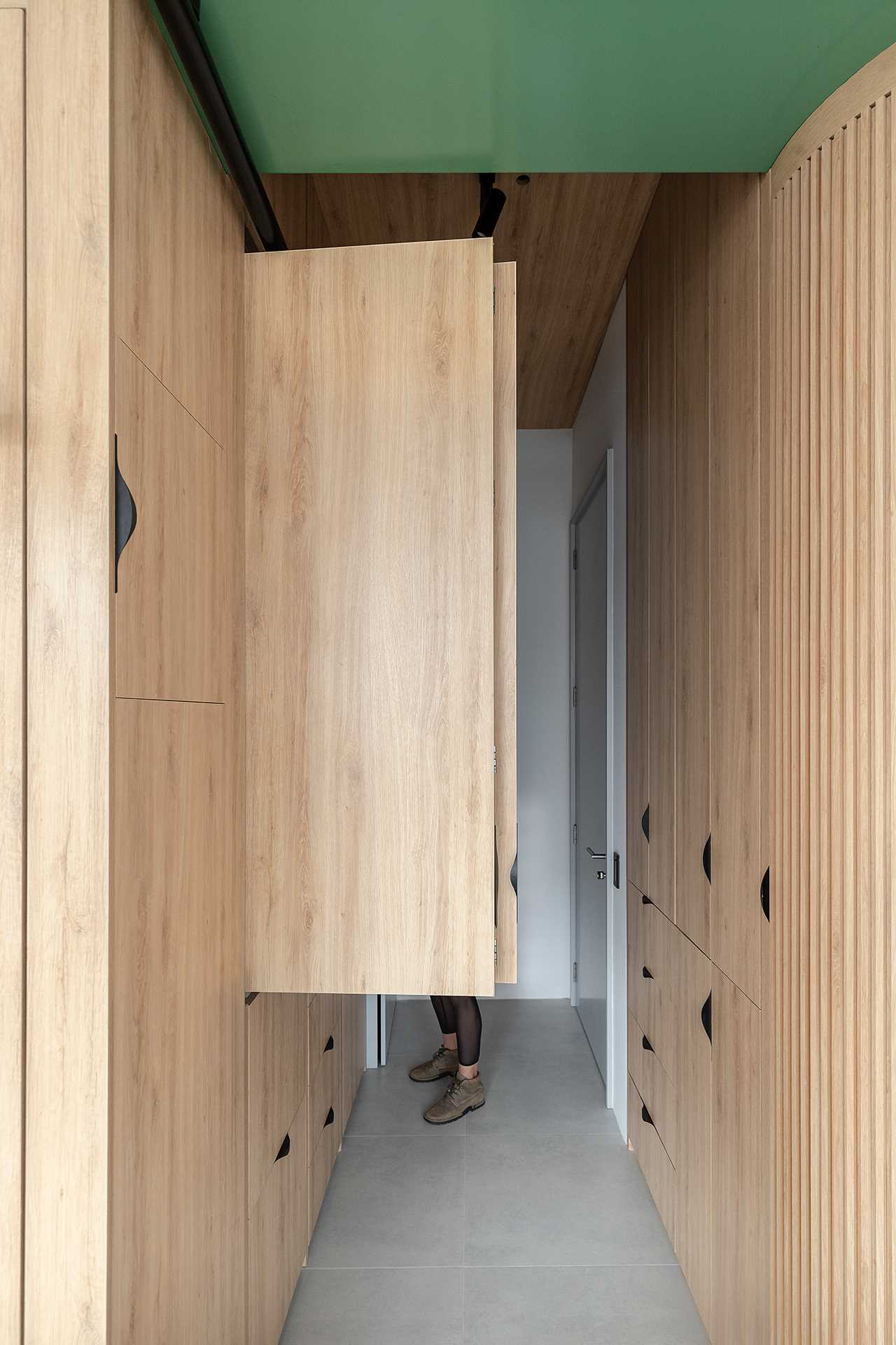 A small kitchen is hidden behind cabinet doors in the hallway of this small apartment.