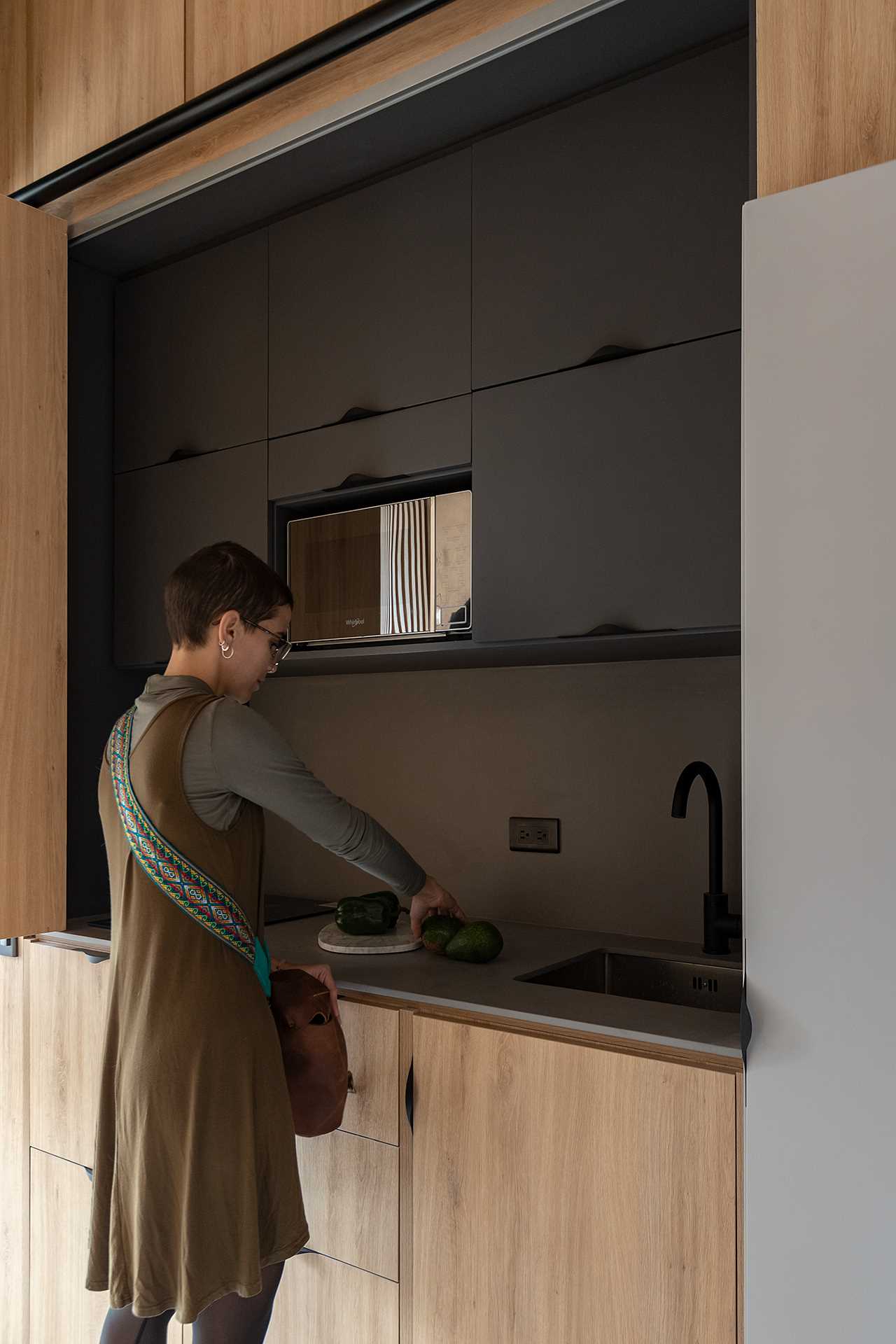 The black kitchen of a small apartment is hidden behind cabinet doors.