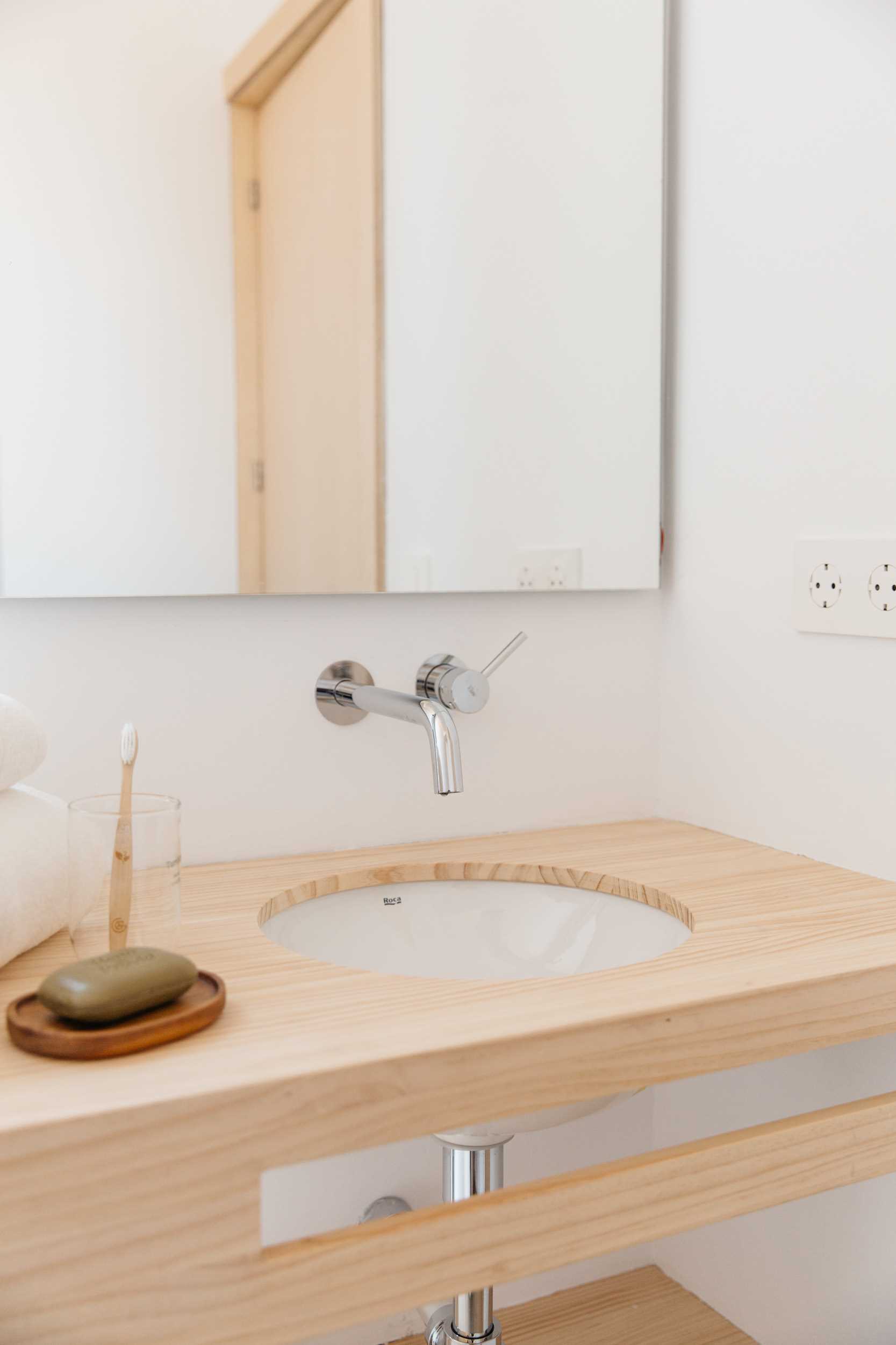 A modern tiny house bathroom has a wood vanity.