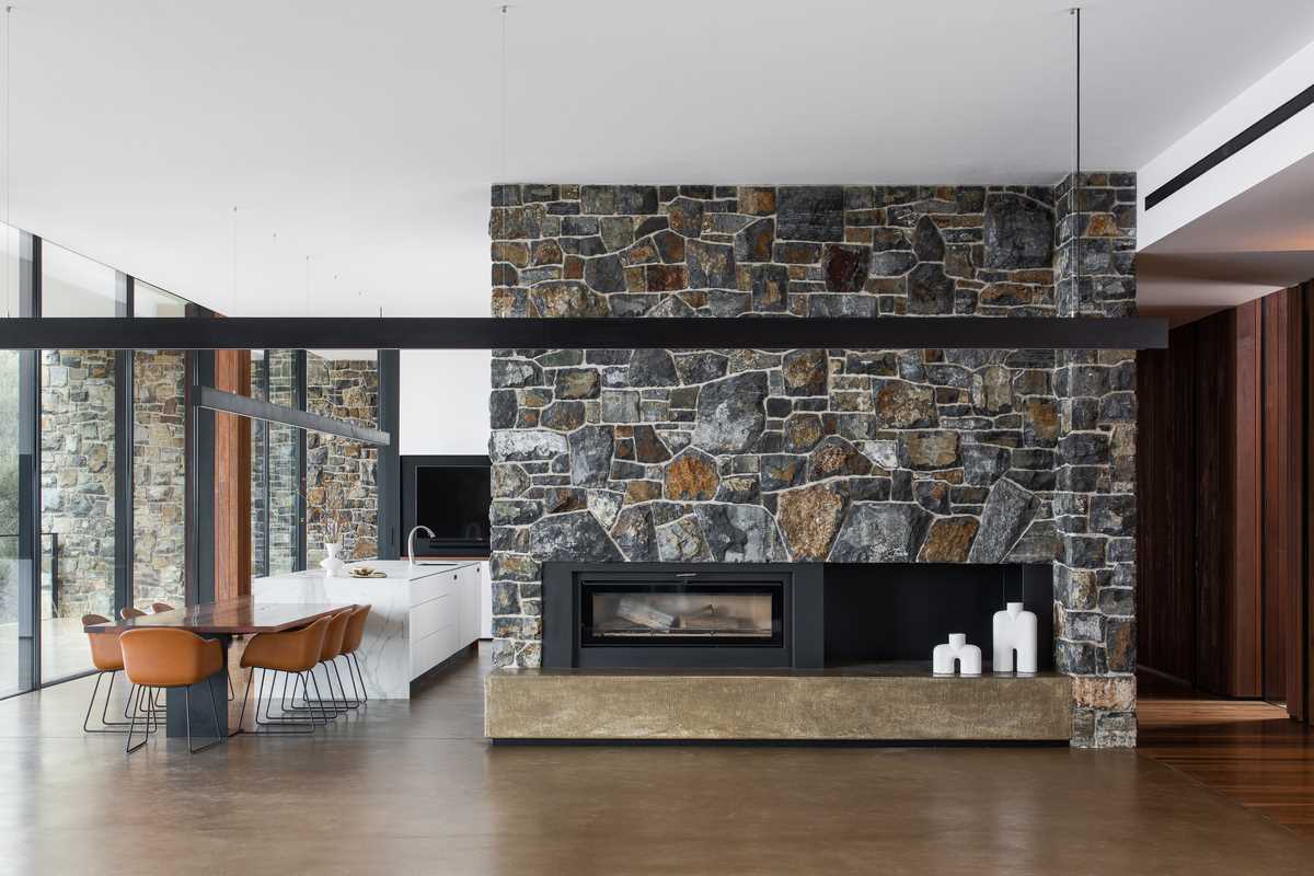 A fireplace embedded into the stone wall can be enjoyed in the dining area that separates the living room from the kitchen.