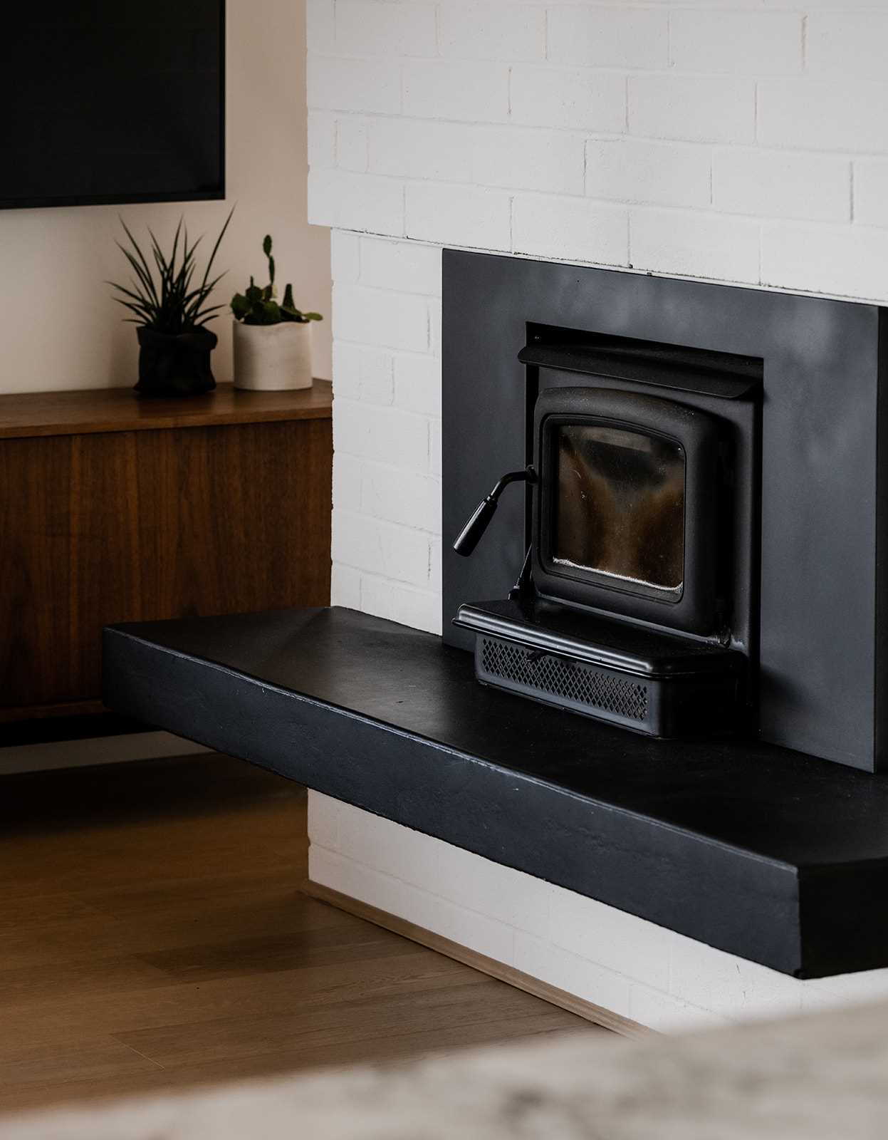 A black fireplace surrounded by white painted brick.